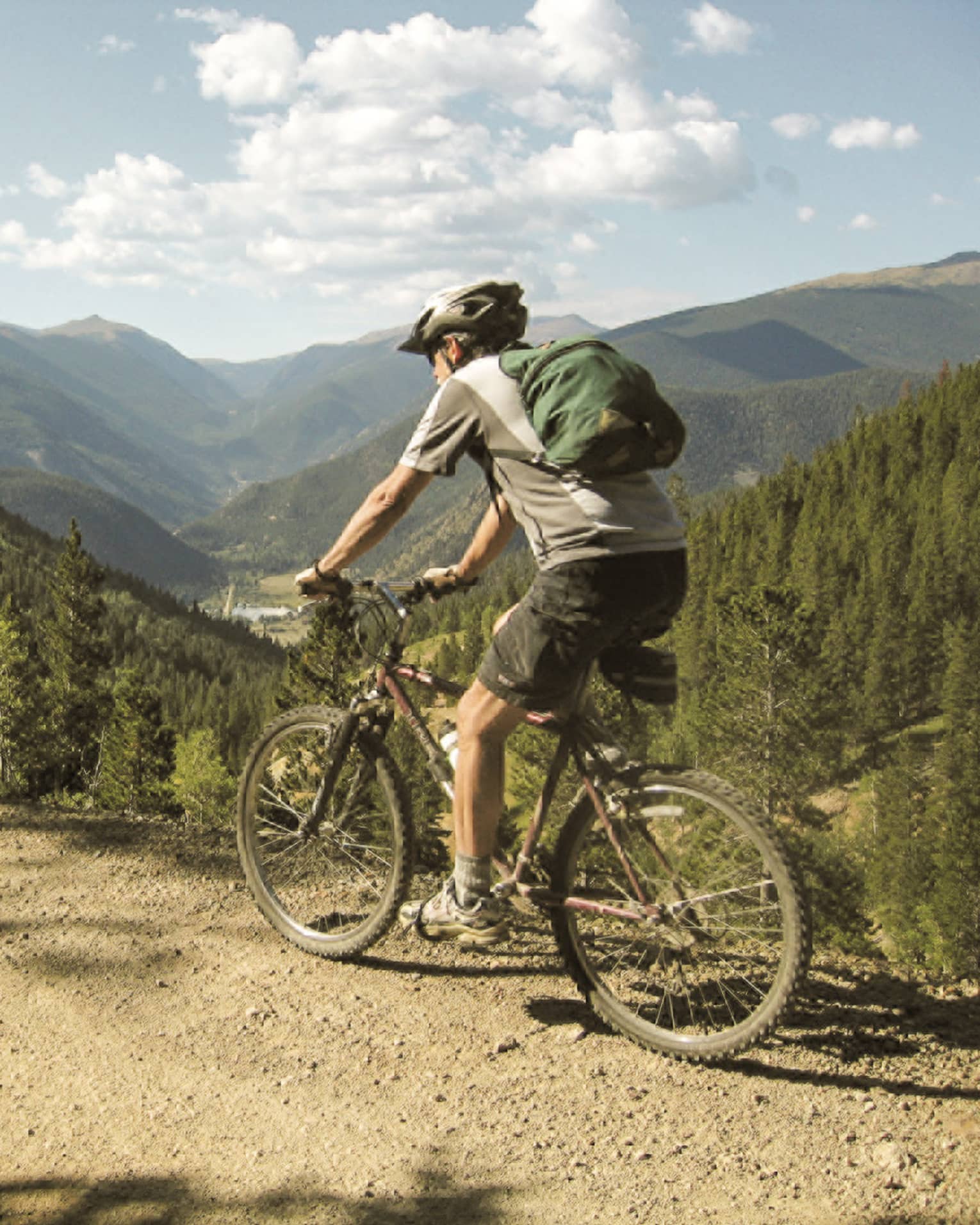 Man in shorts, Tshirt, helmet on bicycle on summer mountain bike trail