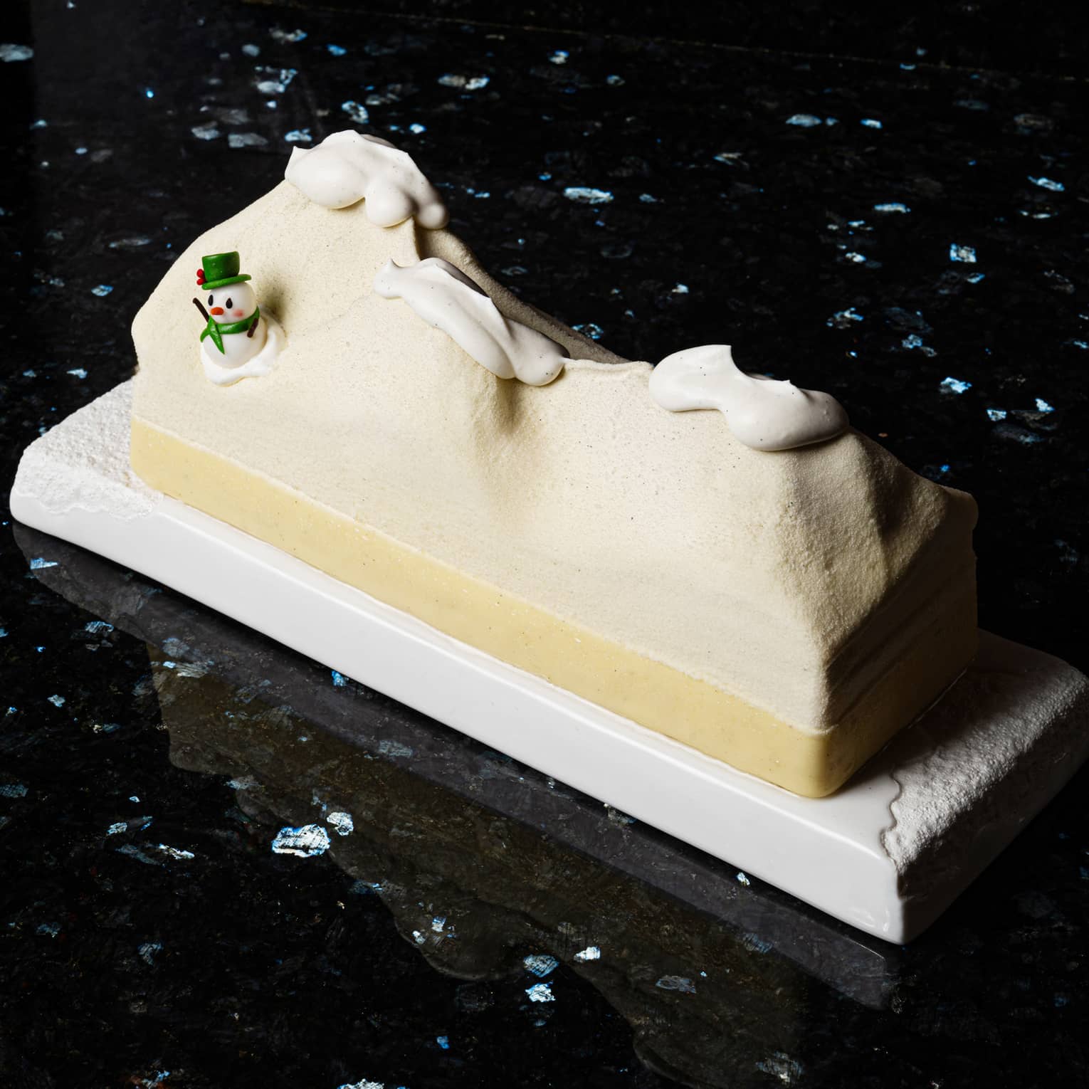 B�che de No�l shaped like desert dunes with snow on top and a snowman on one side