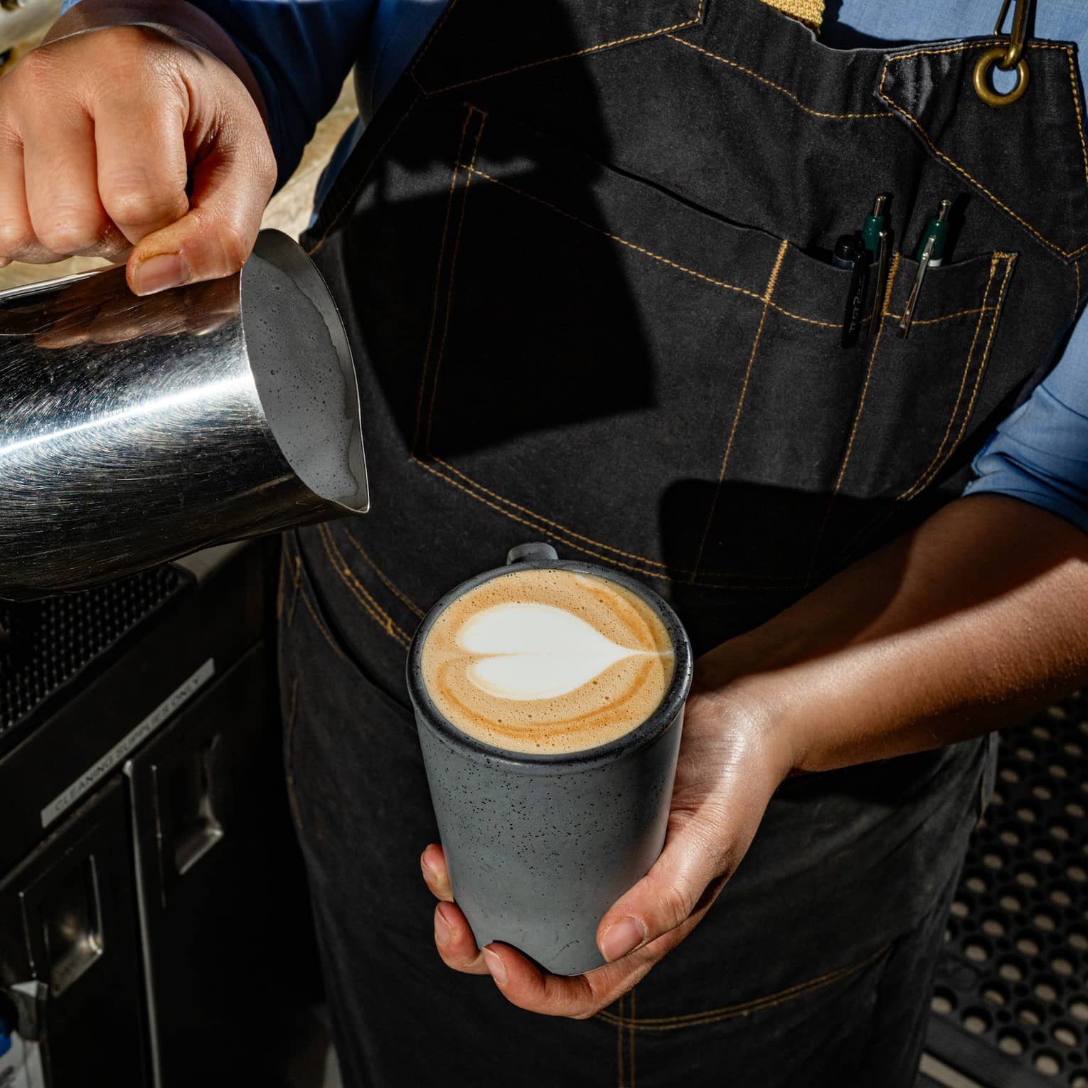 A person pouring milk in a mug of coffee