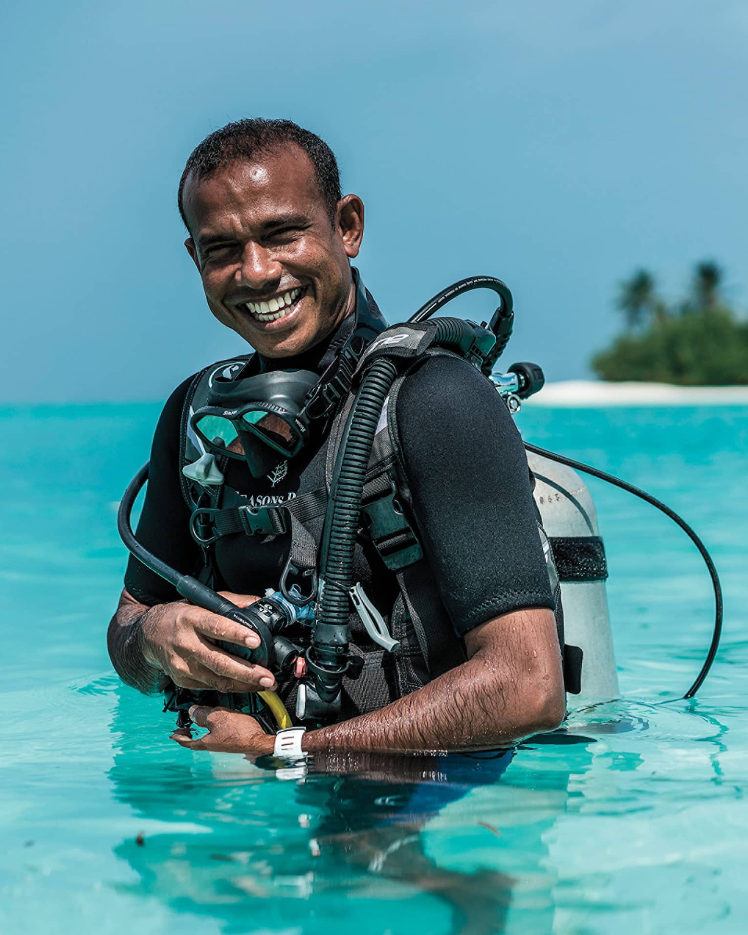 Smiling Dive Manager Ibrahim Nazeer with scuba gear in the crystal clear waters of the lagoon