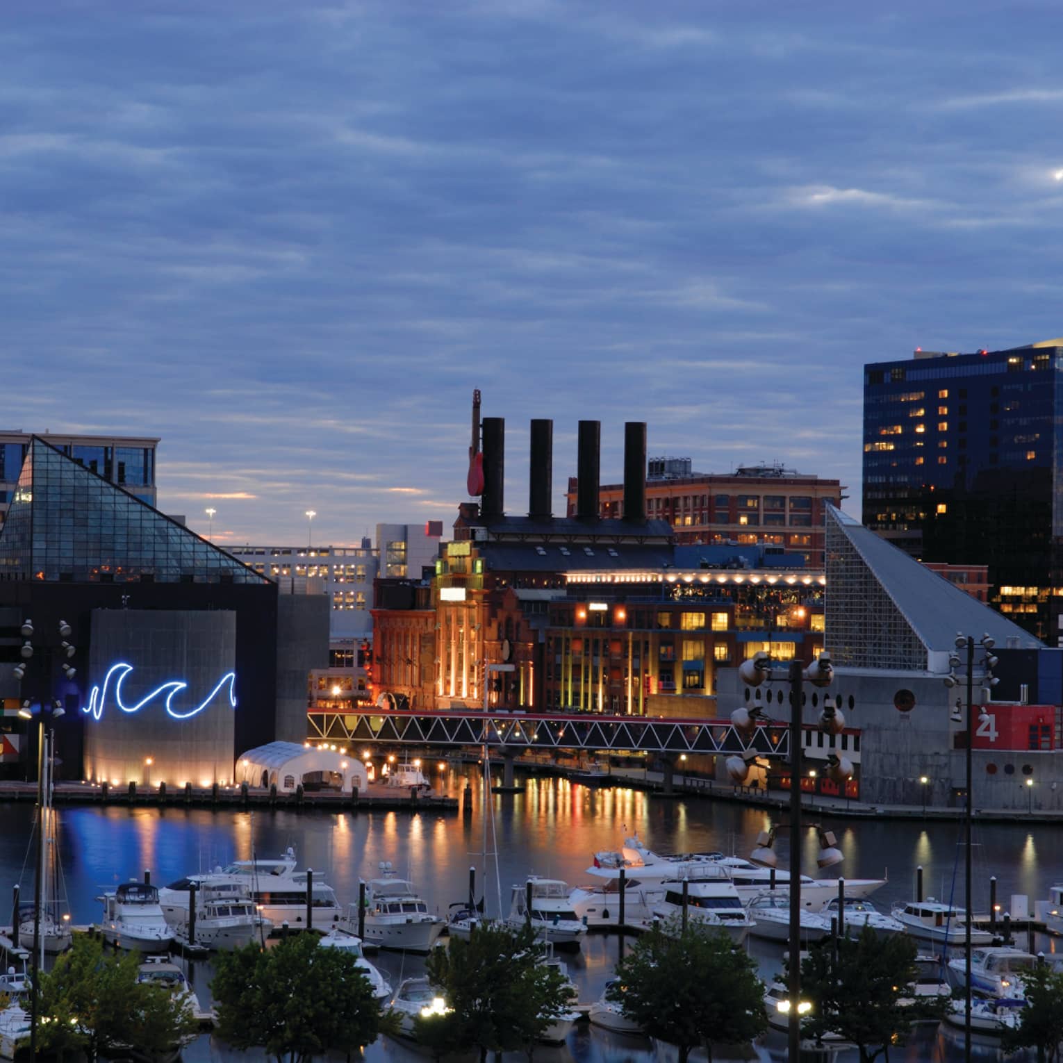 Baltimore buildings with fluorescent wave lights, boats in harbour at dusk