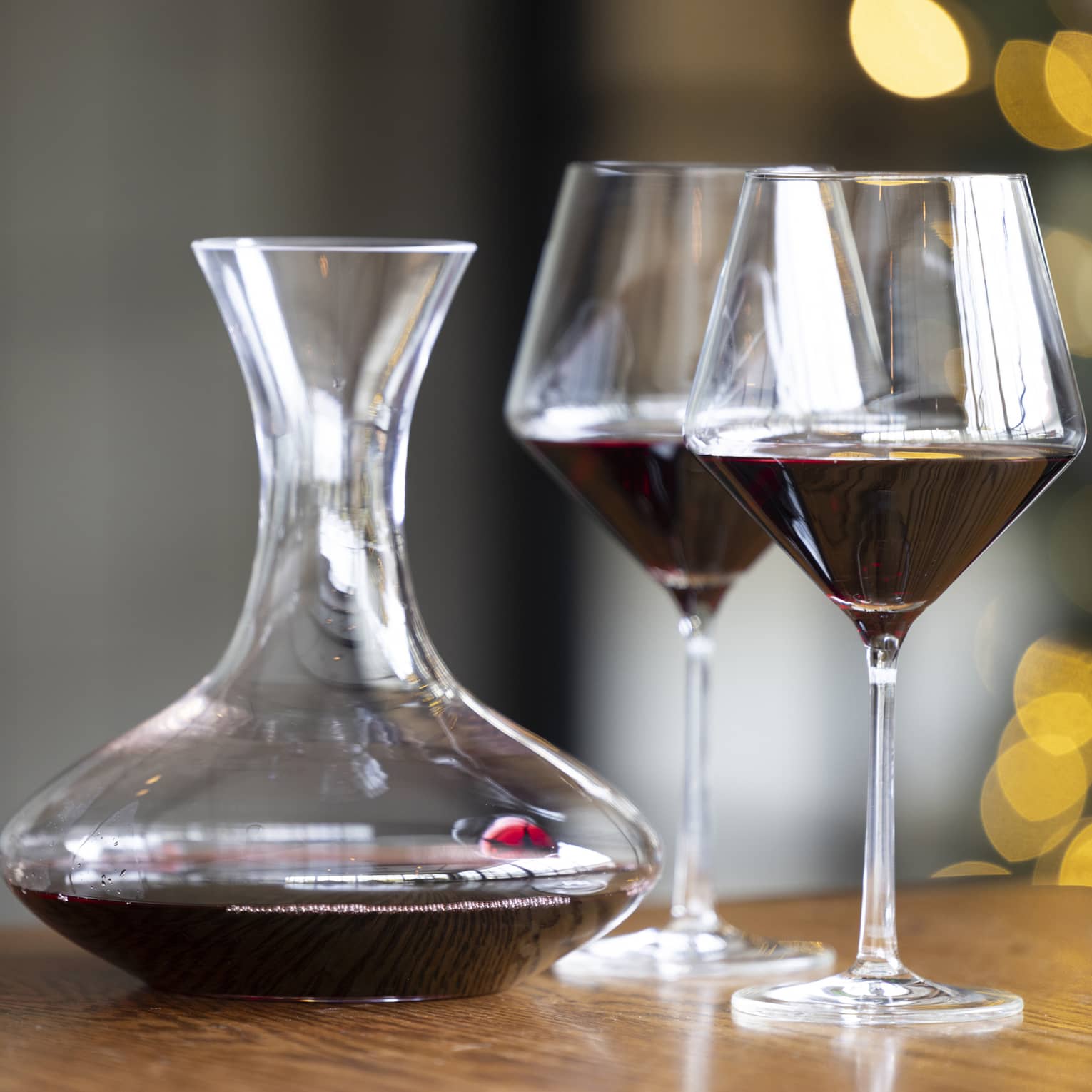 Two wine glasses on a table beside a wine pitcher