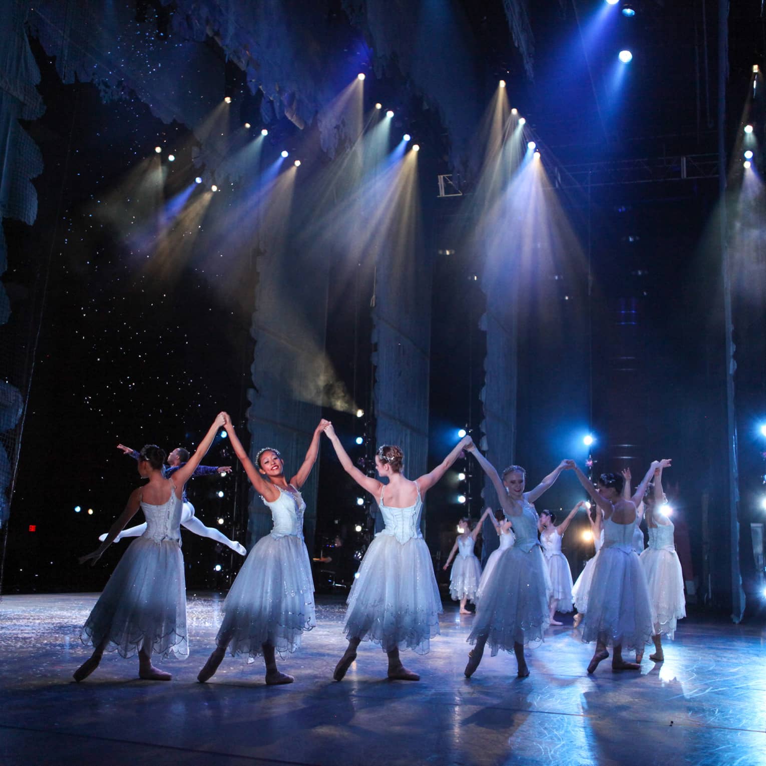 Ballet dancers wearing silvery blue costumes dance on a stage