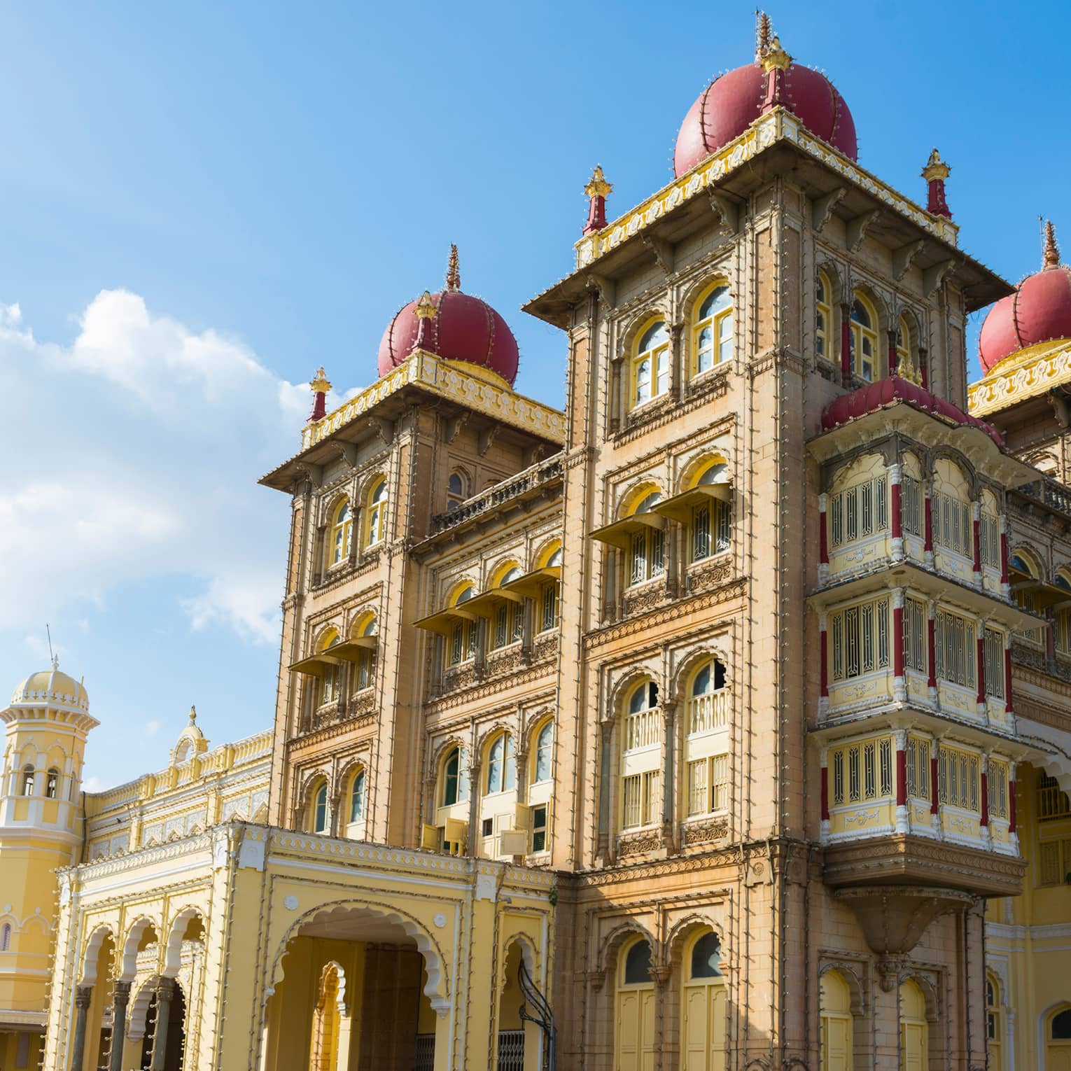 Sprawling palace with arched windows, dome-topped towers and an ornate design, its golden hue contrasted against a sunny sky.