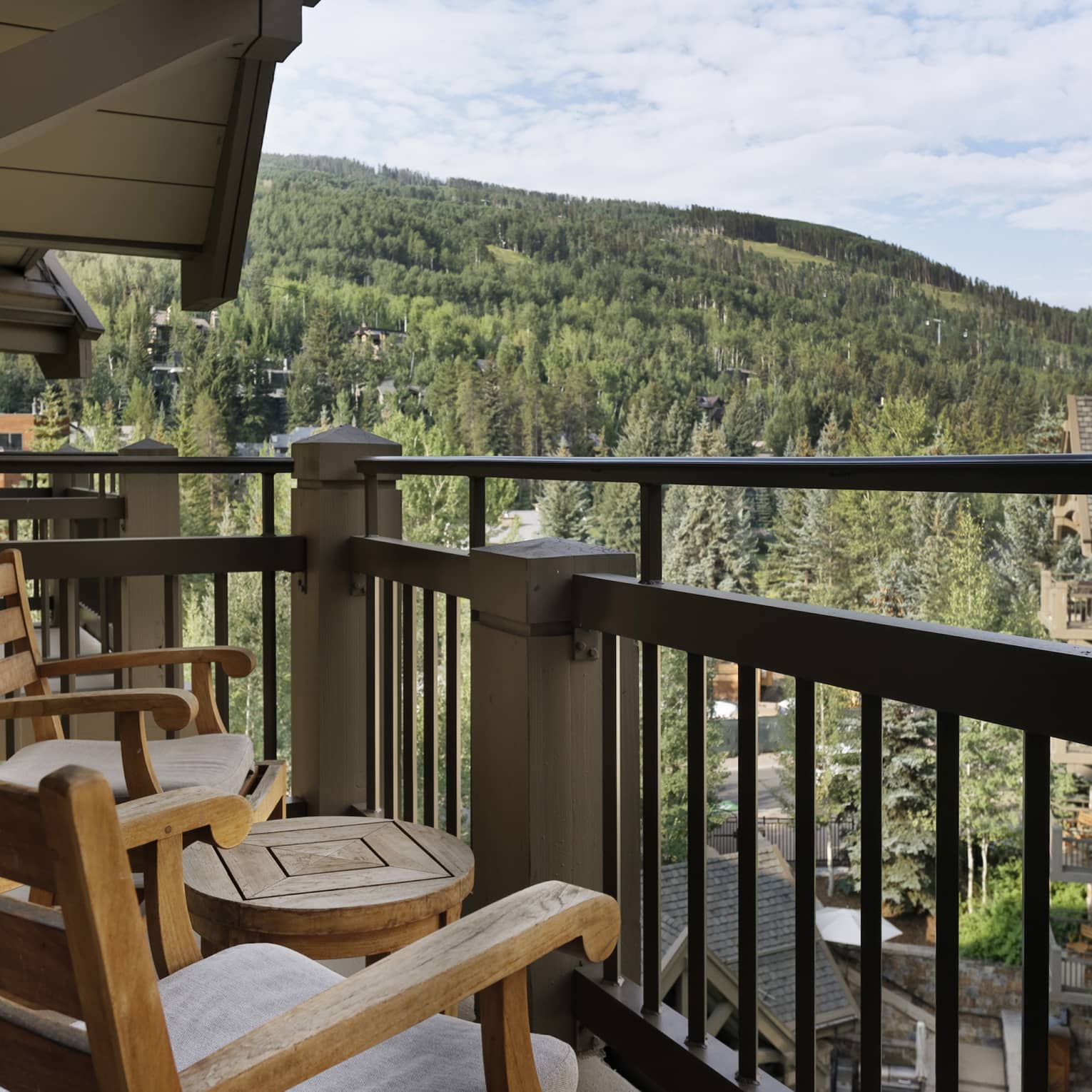 Balcony with portico, two wooden rocking chairs and small round table, mountain views