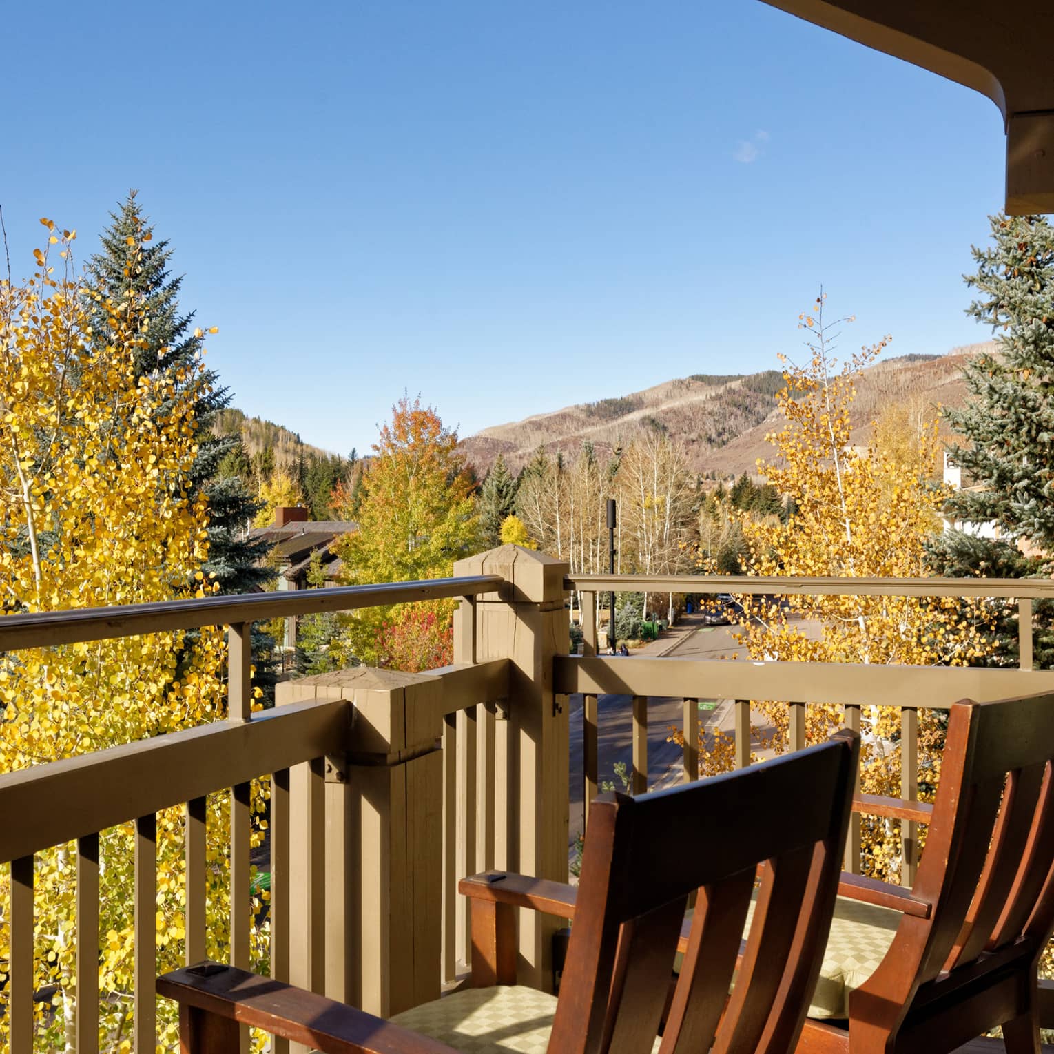 Balcony with two wooden chairs looking out to mountains and trees