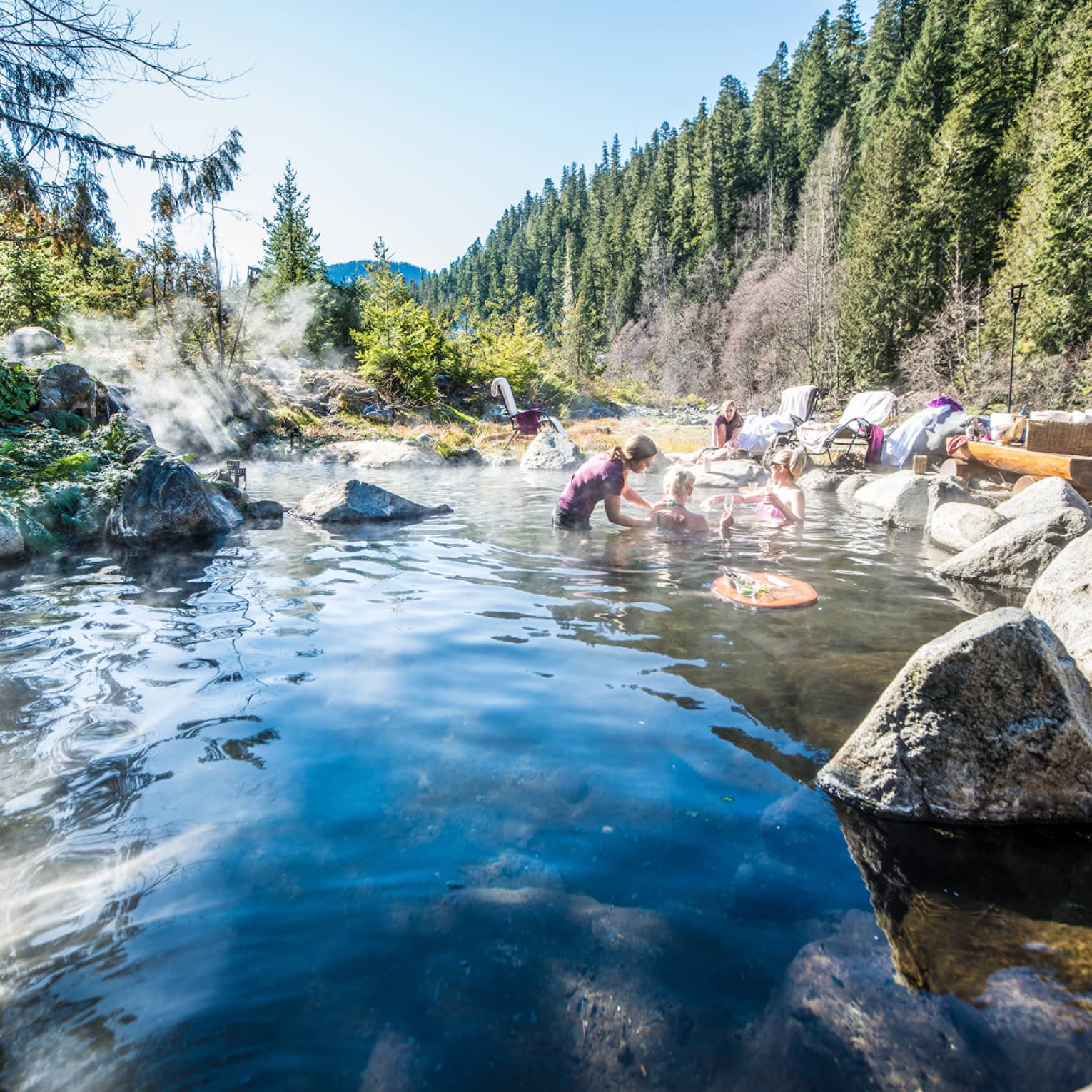 Group relaxes in hot springs, surrounded by forest 