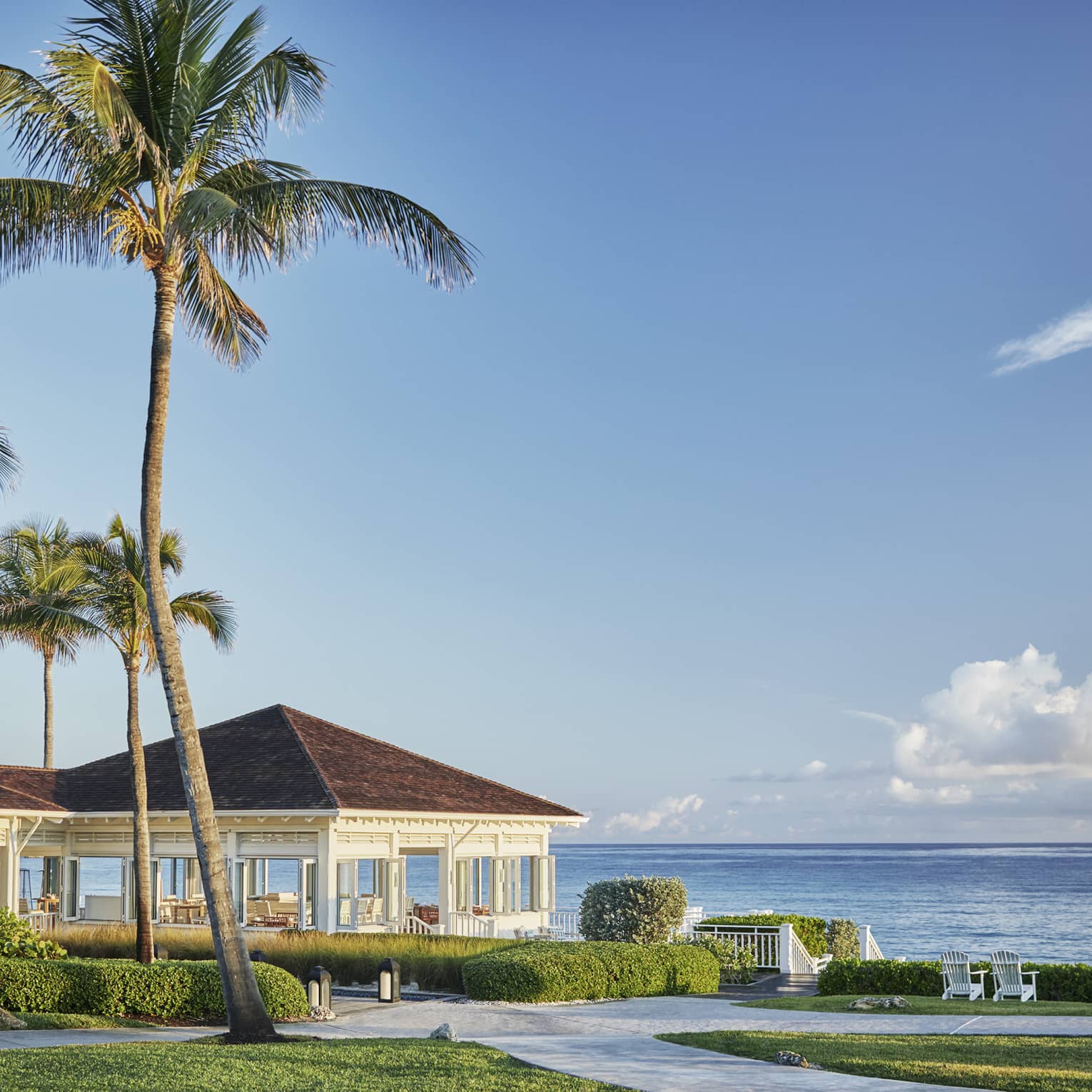 Oceanfront restaurant Dune's pavilions and palm trees, sunny skies over ocean