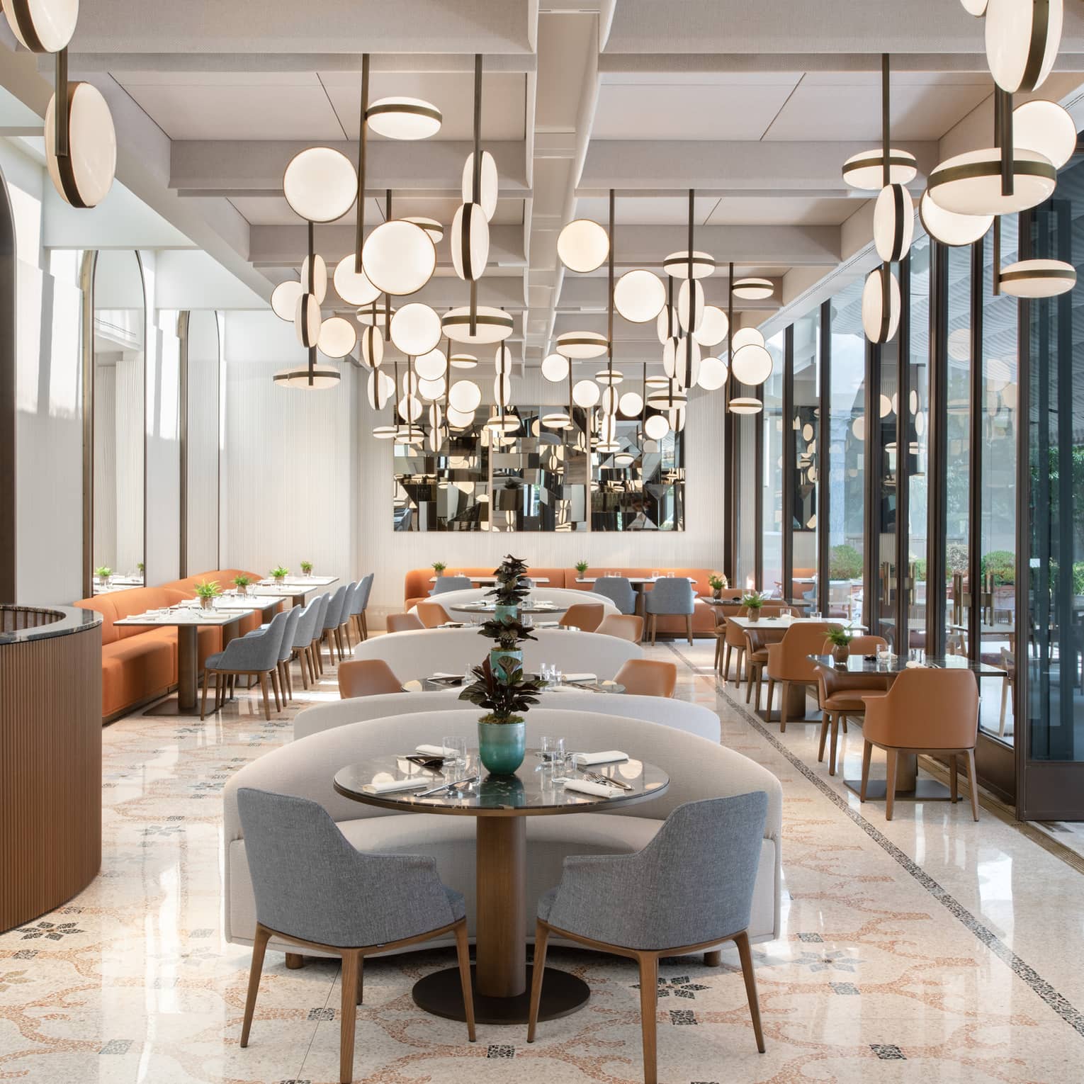 A cleanly decorated dining room with an array of unique lighting fixtures above