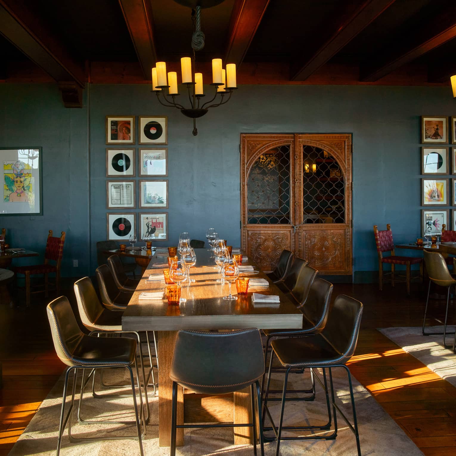 Dining room with blue walls and two chandeliers with candle lights.