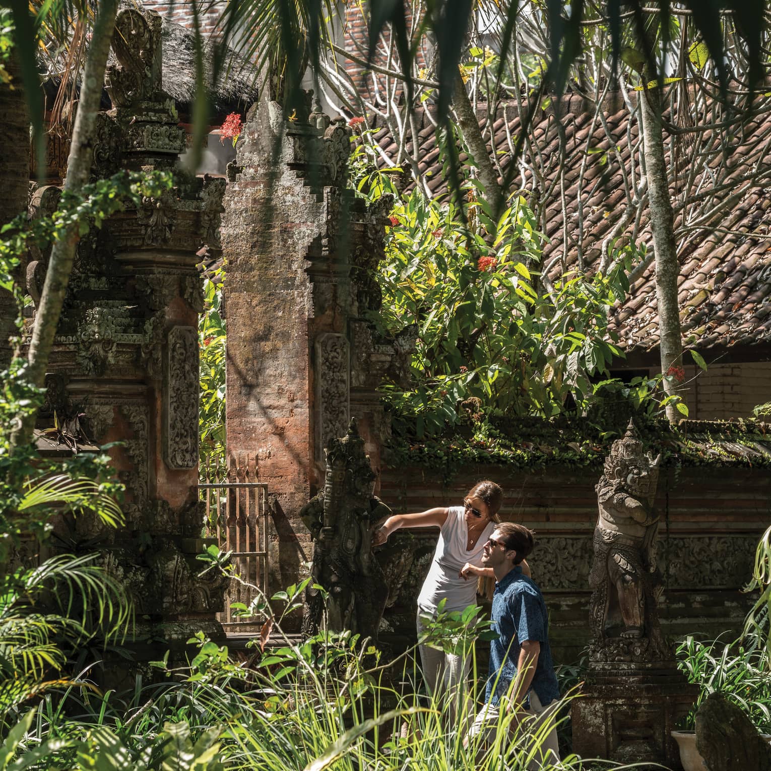 Gusts exploring decorative statues surrounding a temple in Bali