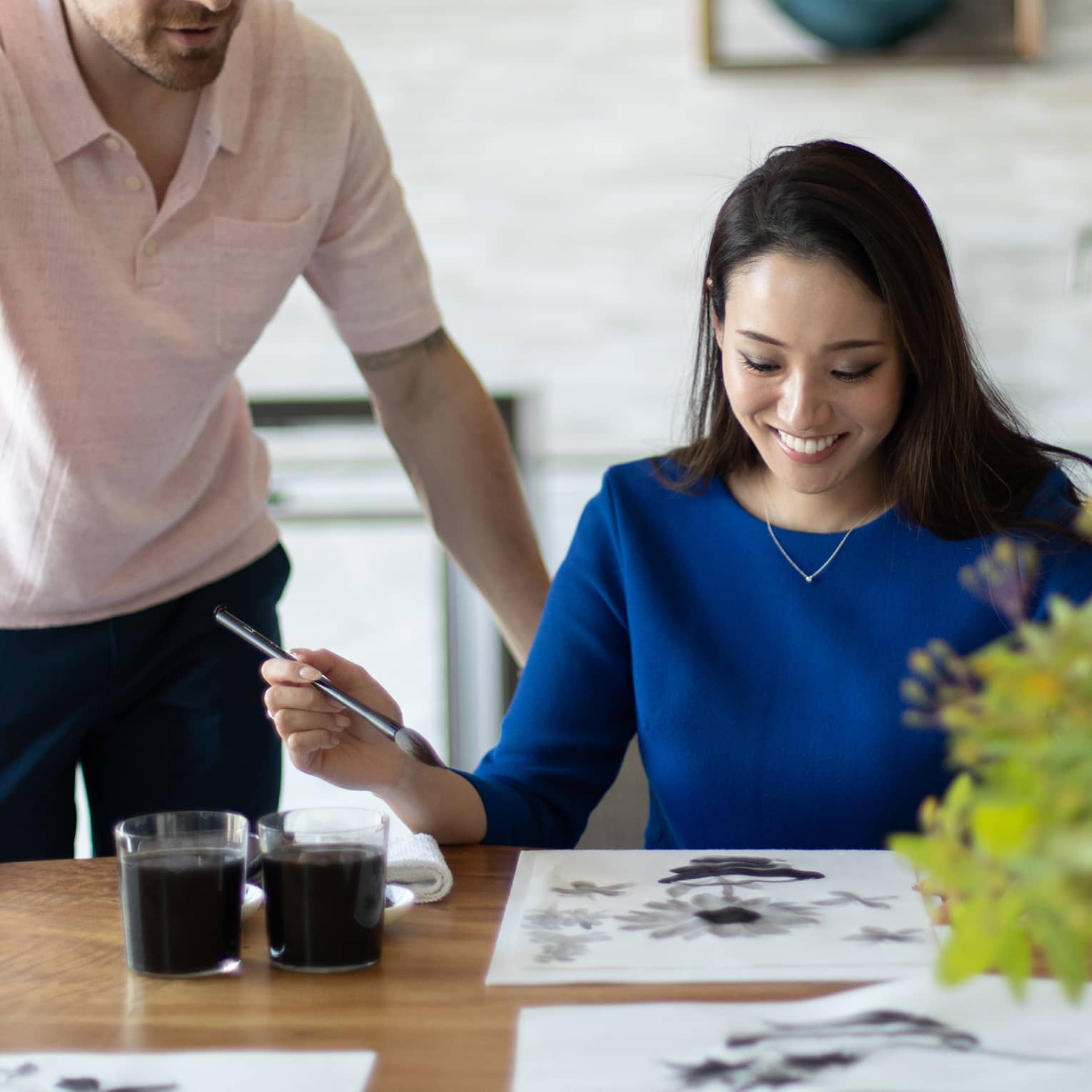 Person smiling while painting with watercolours at a table