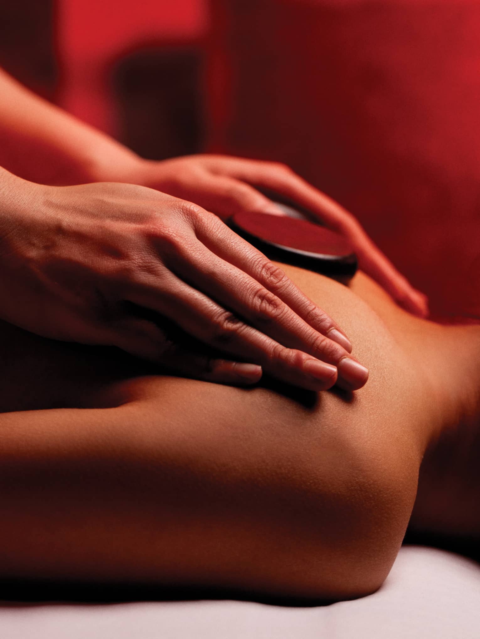 Hands rub woman's bare shoulders during Fusion Massage in spa