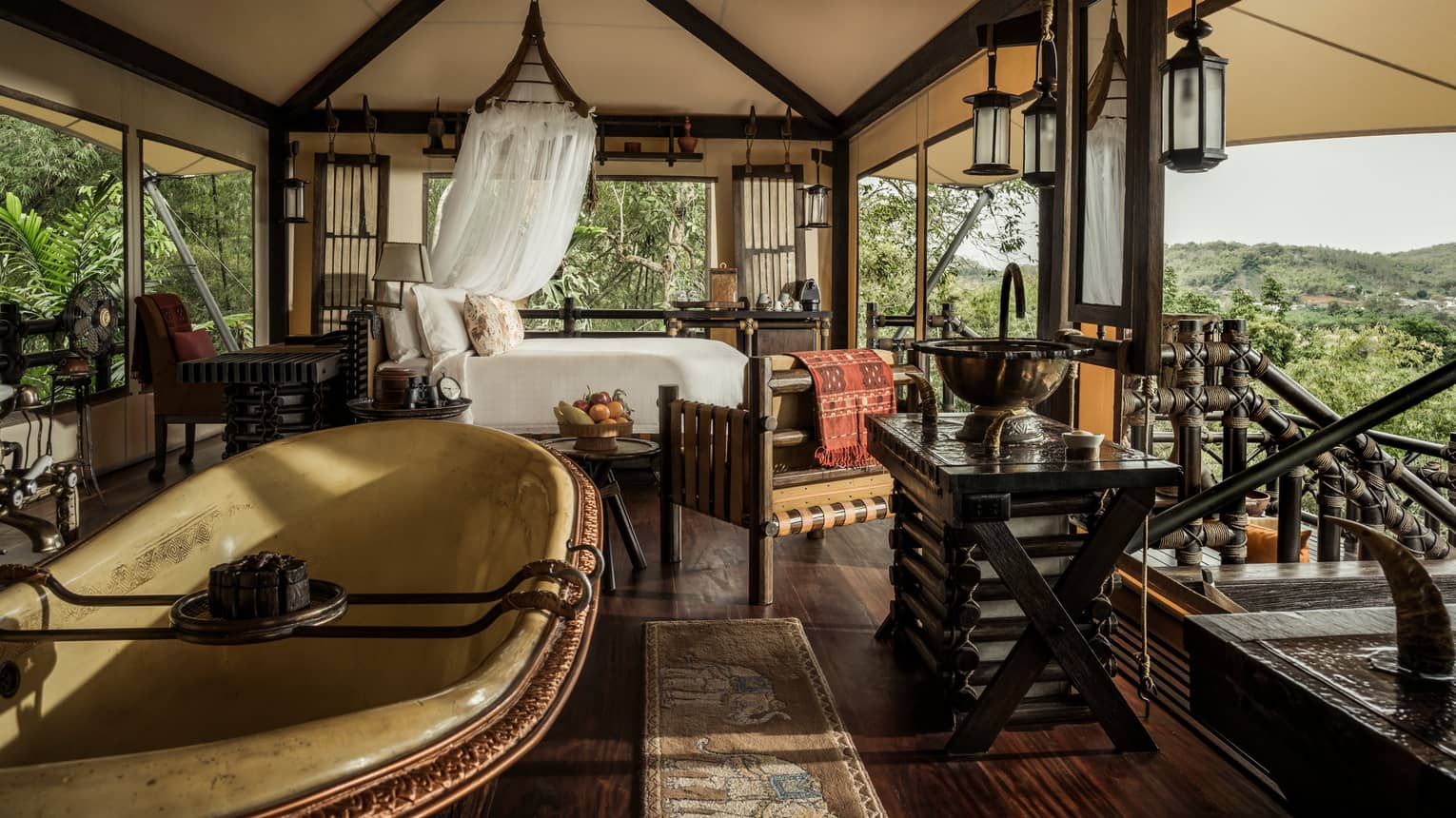 Outdoor open-air room with bed, tub, lanterns and mountain views