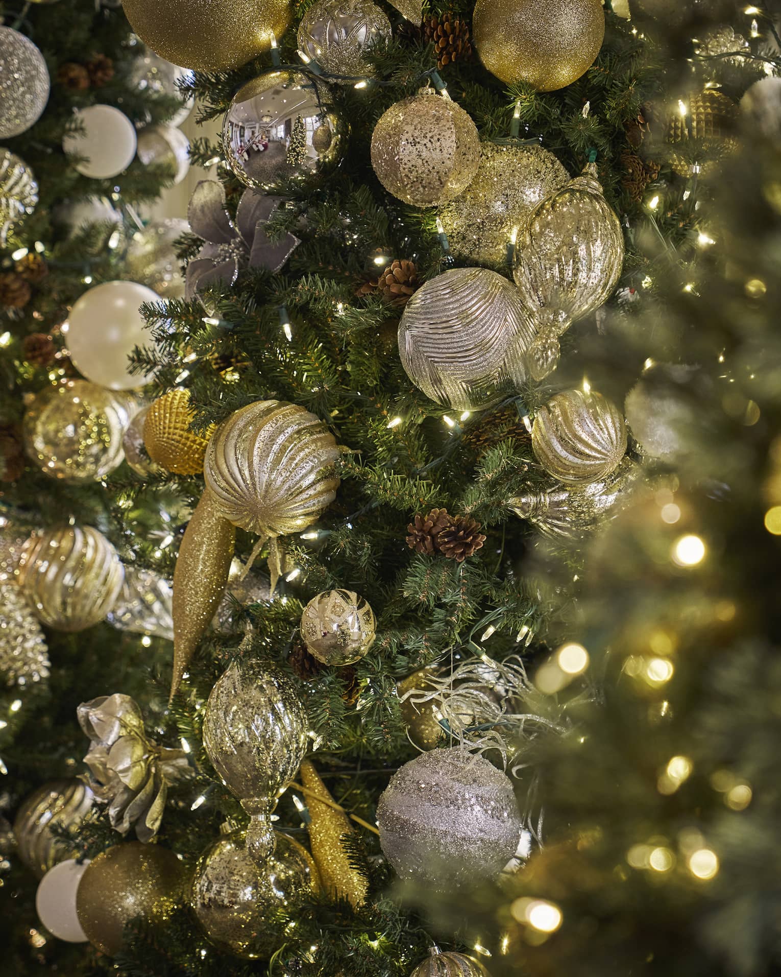 Closeup of Christmas tree with gold ornaments and white string lights