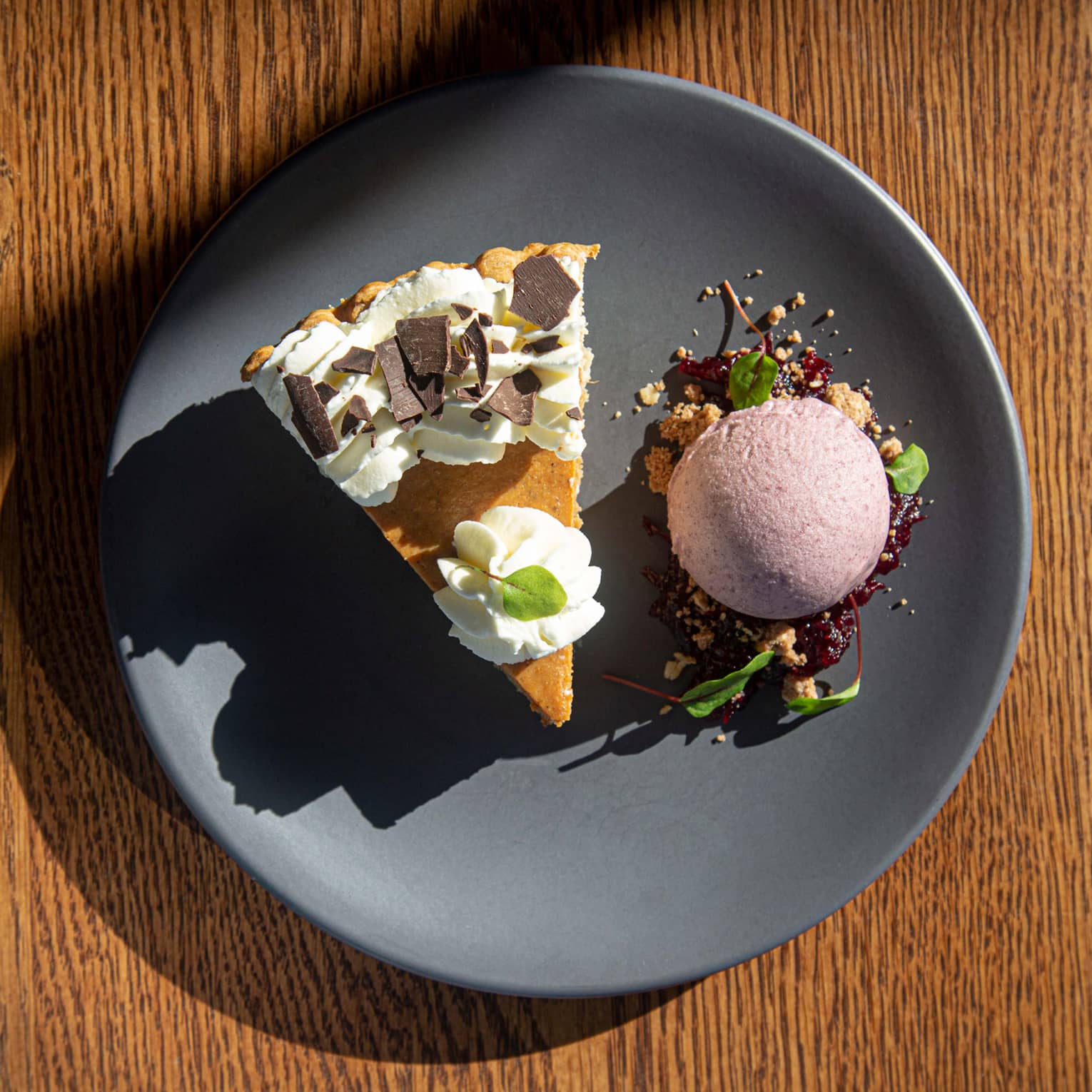Pumpkin pie and scoop of ice cream on a dark grey plate