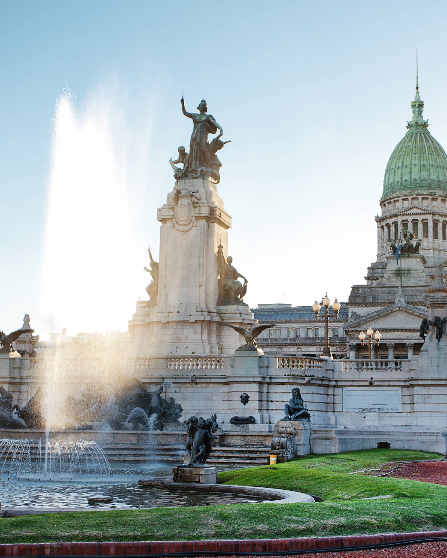 Large fountain, historic building and courtyard on sunny day