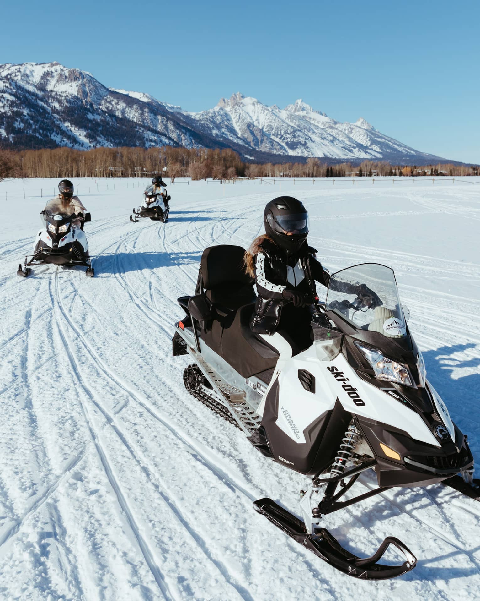Three people on snowbmobiles.