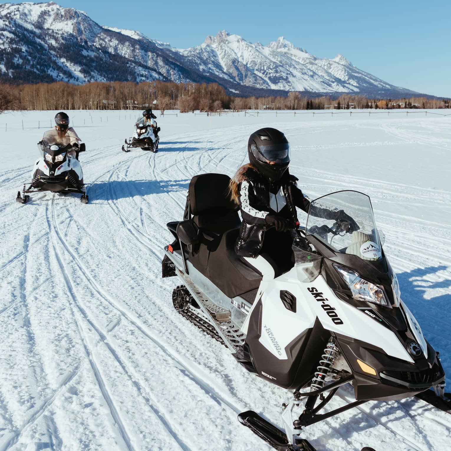 Three people on snowbmobiles.