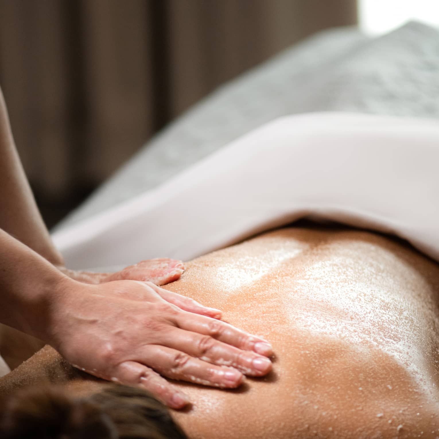 A woman being massaged by a spa staff member while lying down.