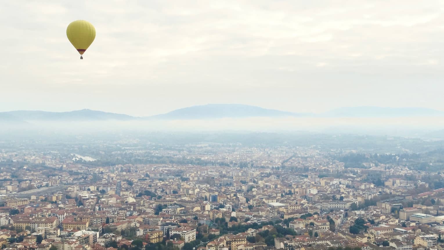 Yellow hot air balloon flying over Florence city