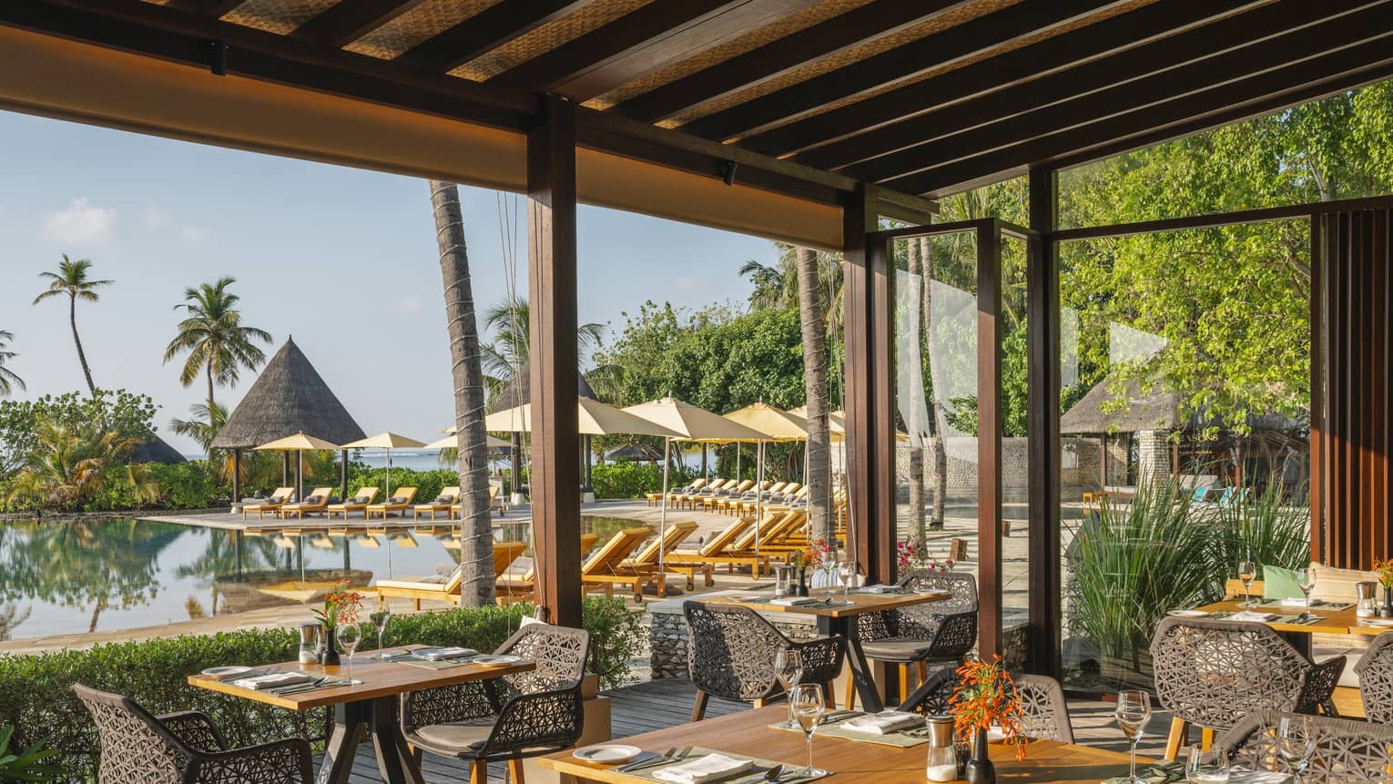 Open-air restaurant Caf� Huraa with rattan chairs and blonde wood tables, overlooking the pool