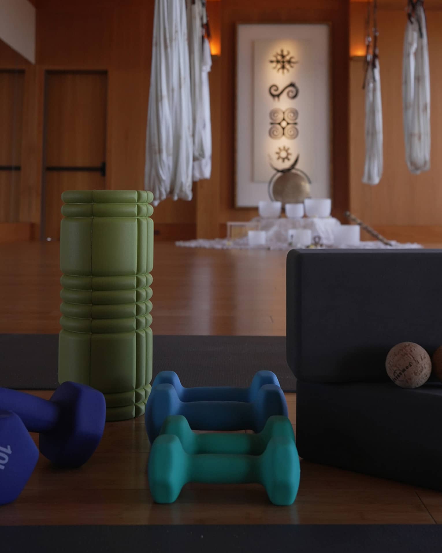 Fitness studio with hanging aerial yoga hammocks weights and a foam roller