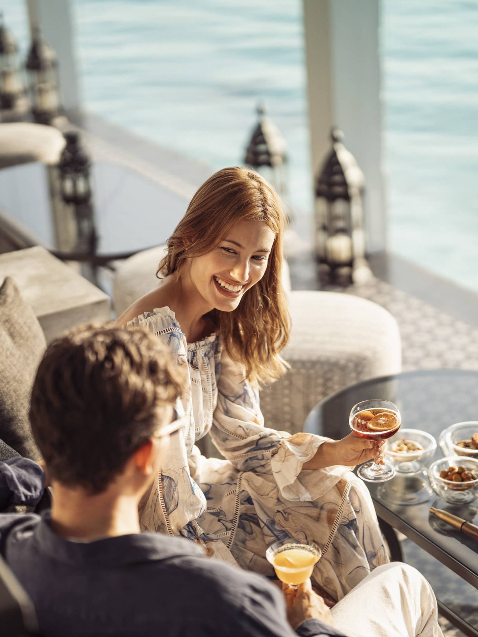 Smiling couple enjoys cocktails on the outdoor terrace of Al Barakat