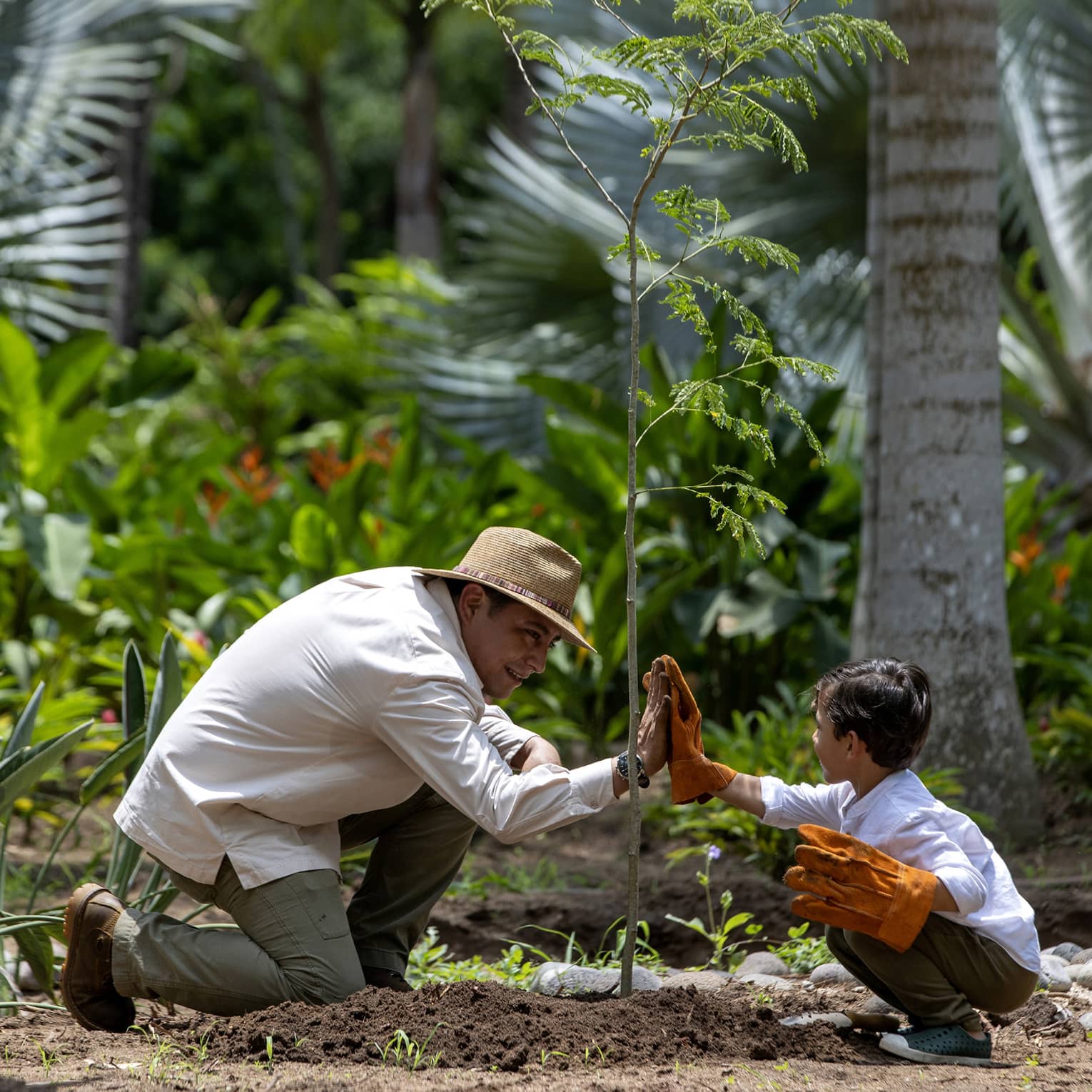 Two guests giving each other a high five while wearing gloves surrounded by nature.