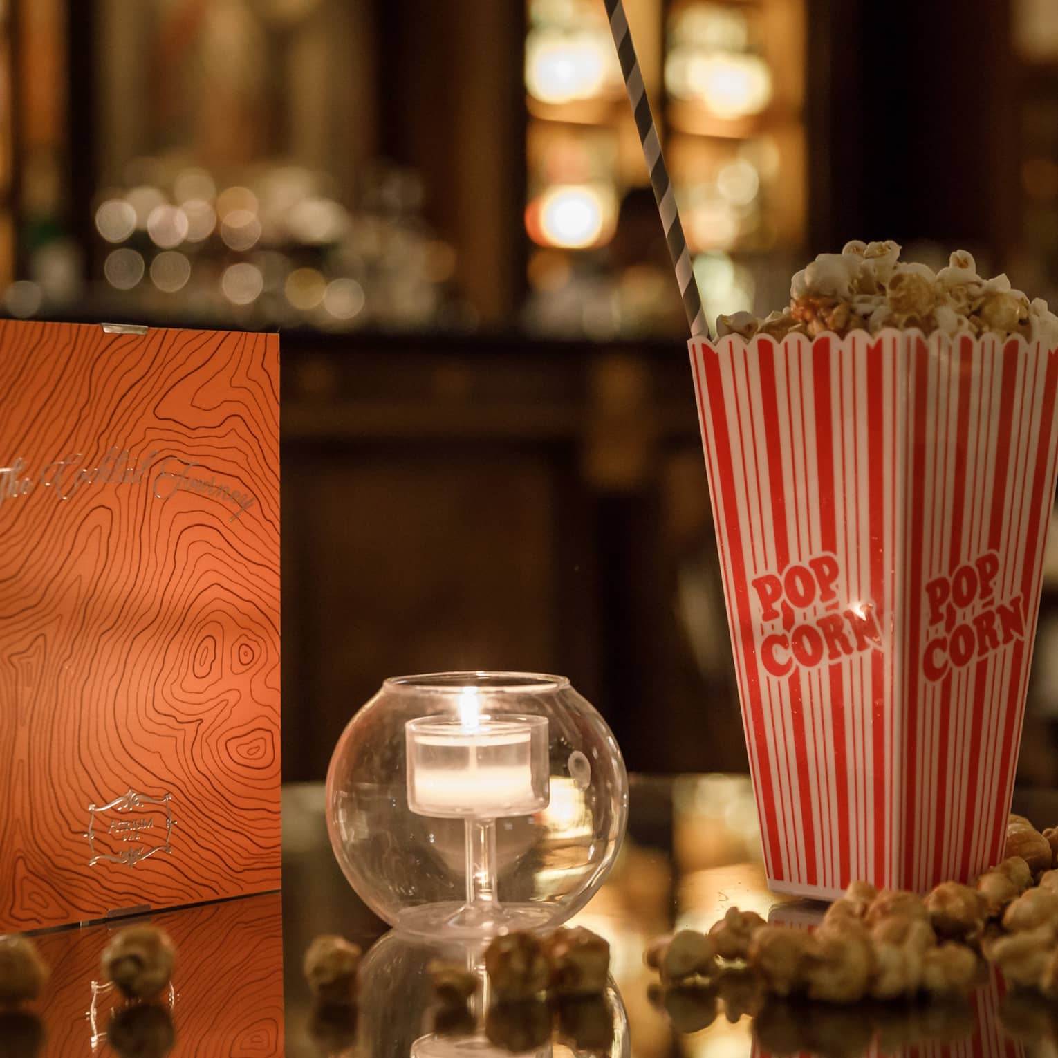 Warmly lit table with movie popcorn and tealight candle.