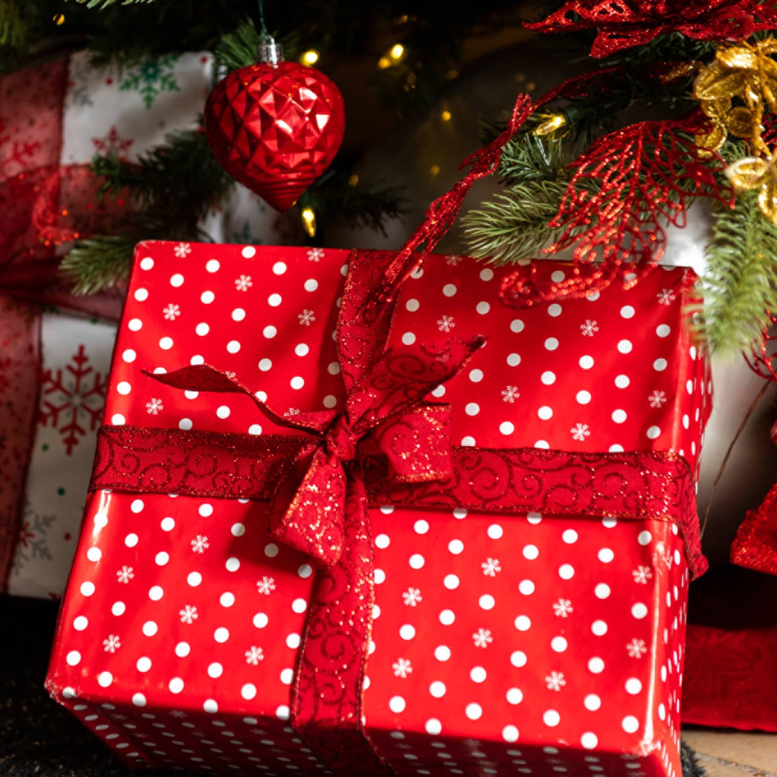 Red and white presents wrapped under a Christmas tree