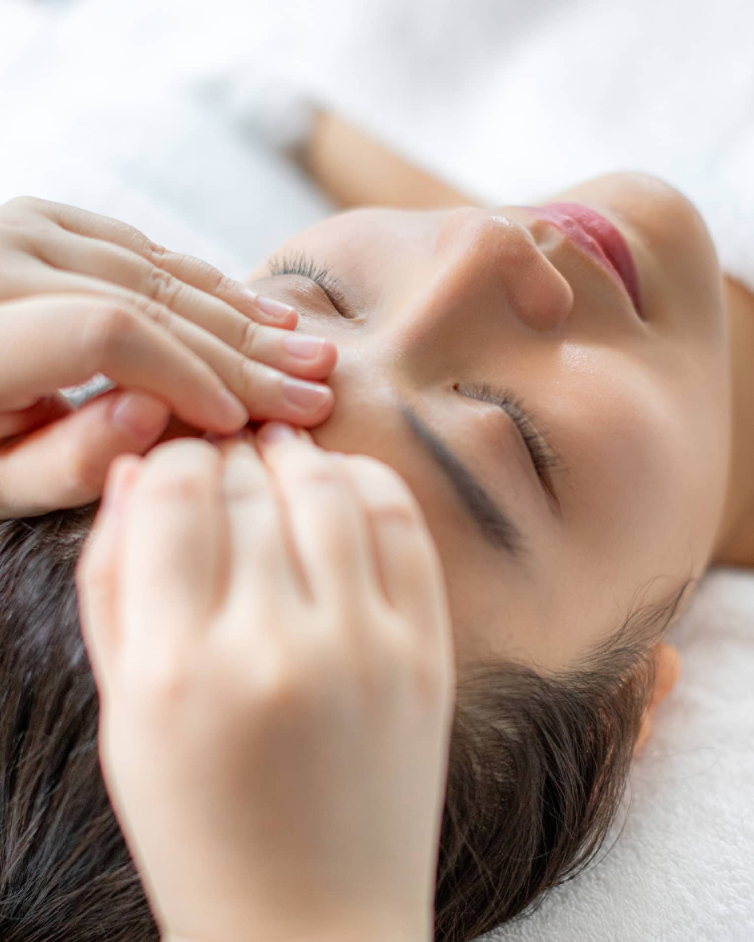 A woman getting a facial massage in a spa.