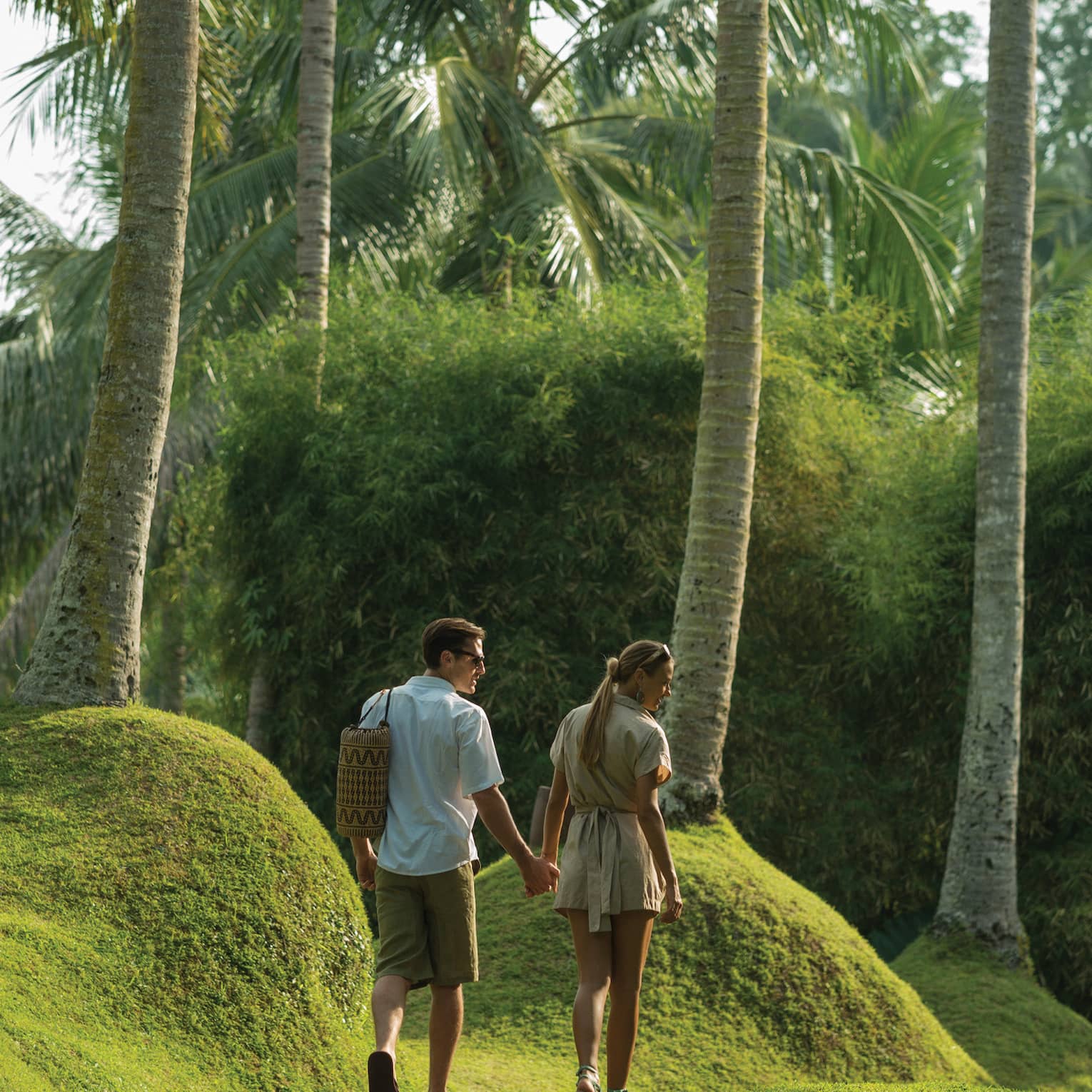 Guests holding hands and strolling through a garden in Bali