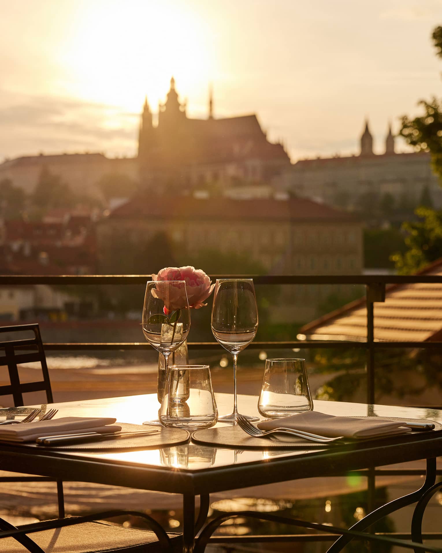 Terrace dining setup at sunset with view of Prague Castle in backdrop