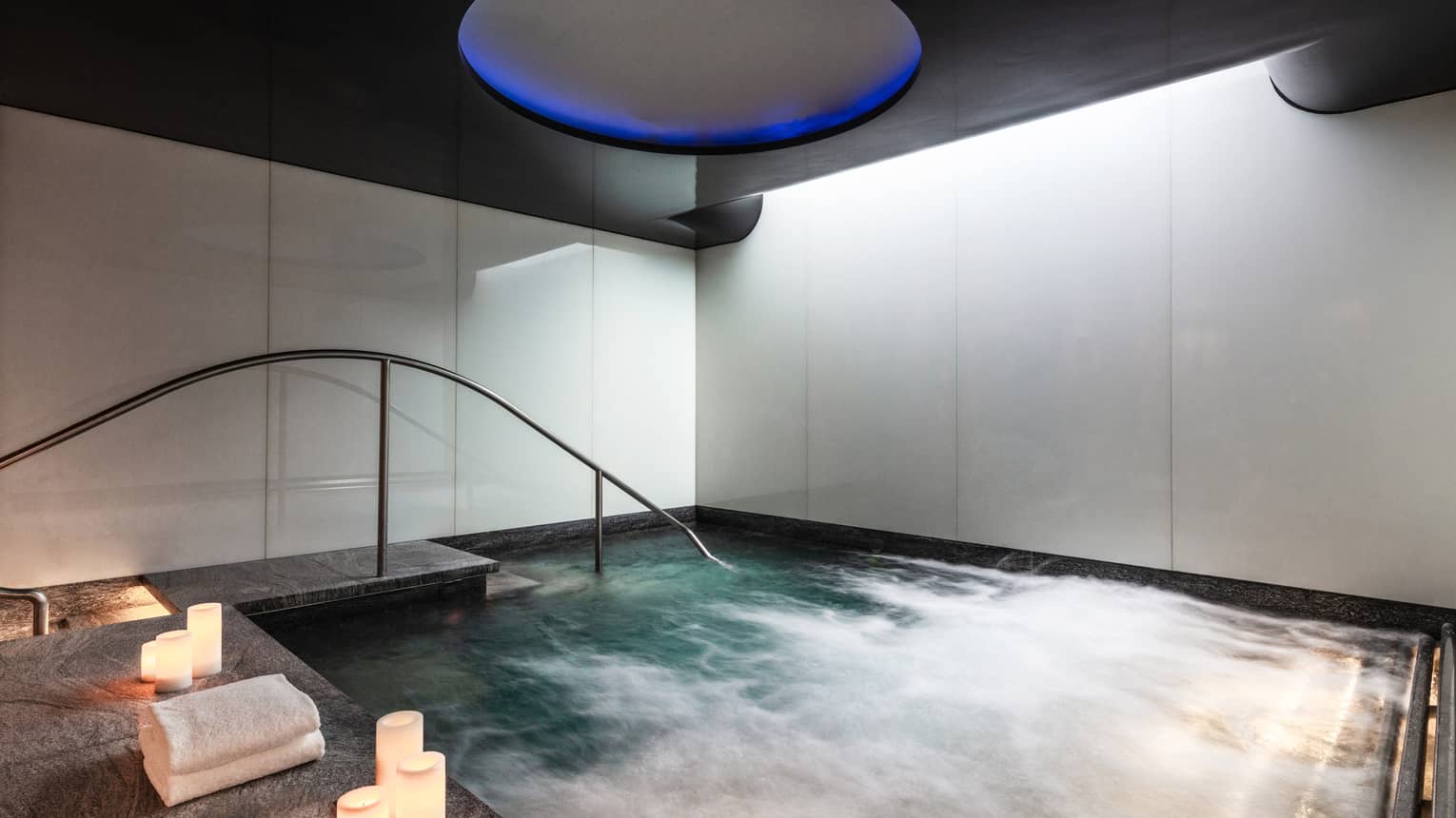 An indoor whirlpool with candle on the ledge.