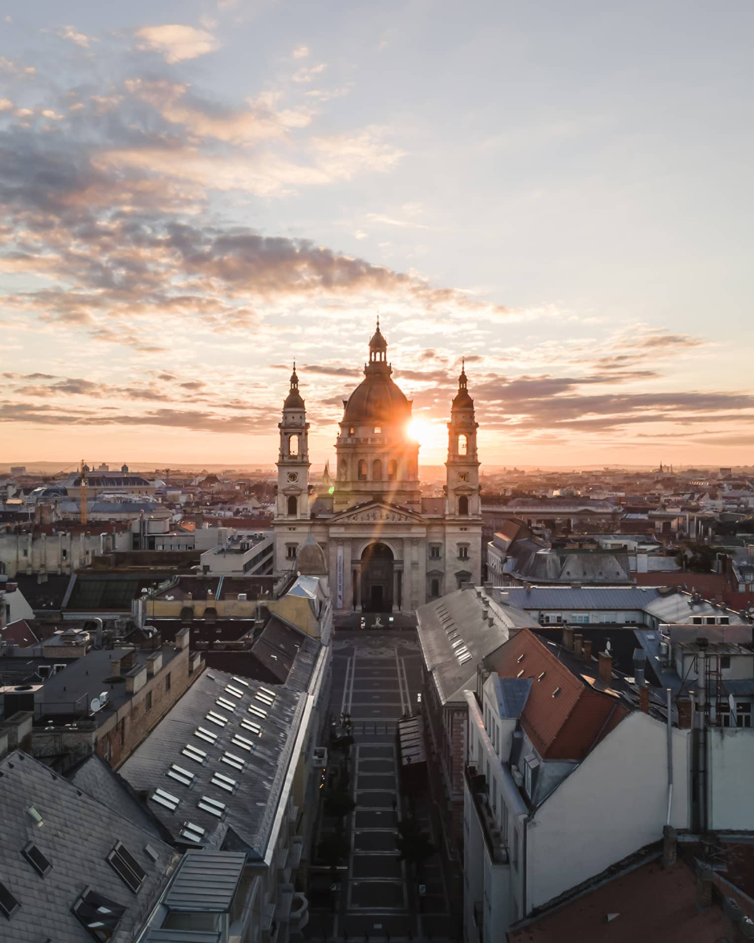 Historic domed cathedral with twin towers at sunrise above city rooftops