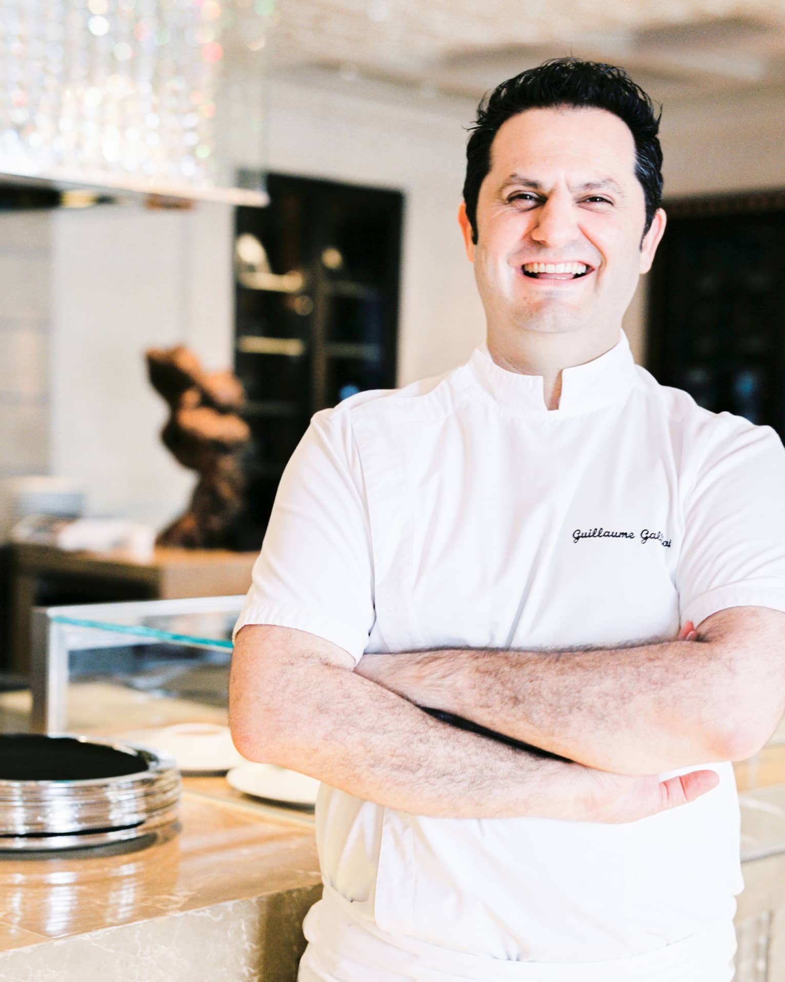 Portrait photo of Chef Guillaume Galliot in uniform and crossing arms