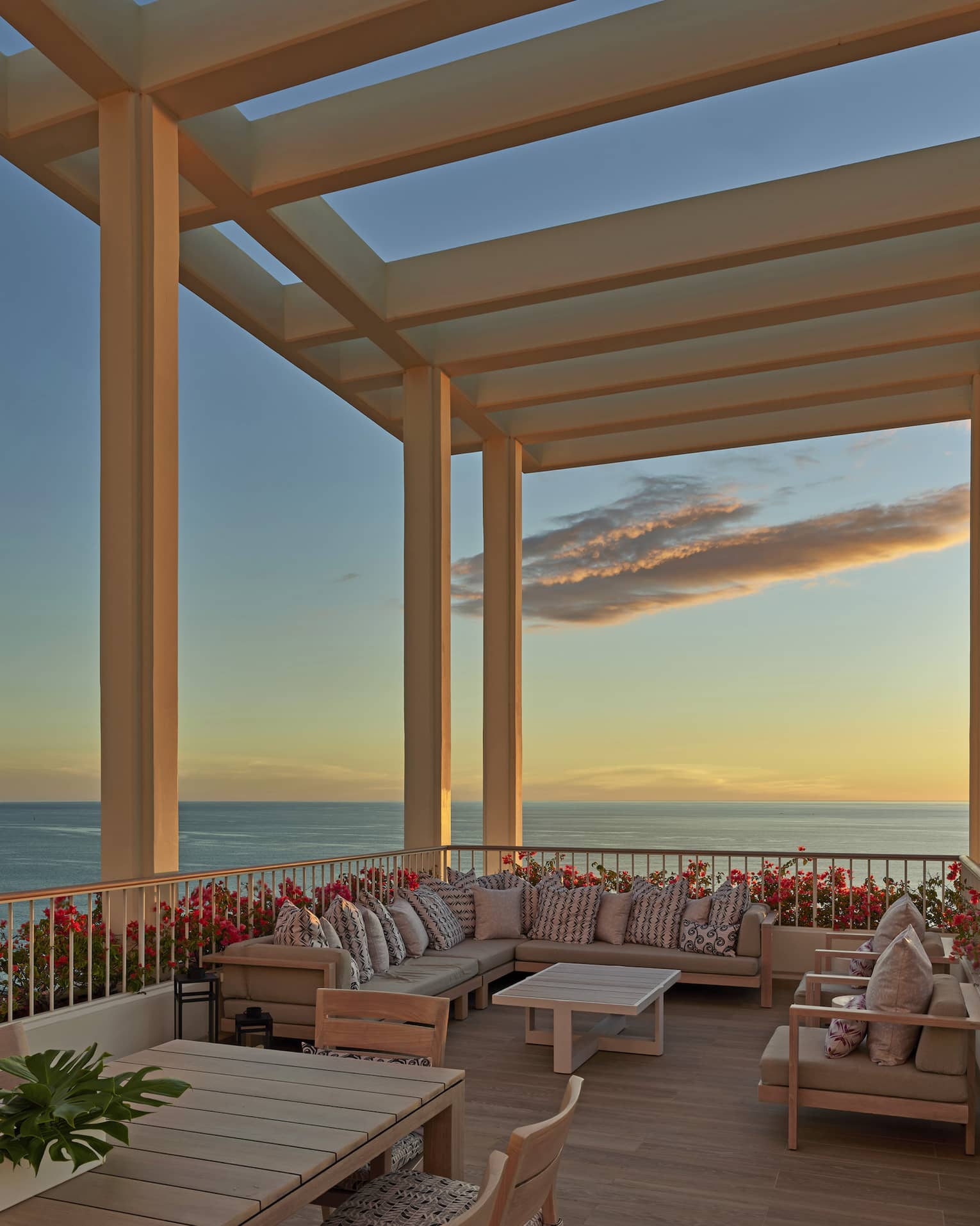 Large lanai overlooking the ocean with lounge furniture and pergola