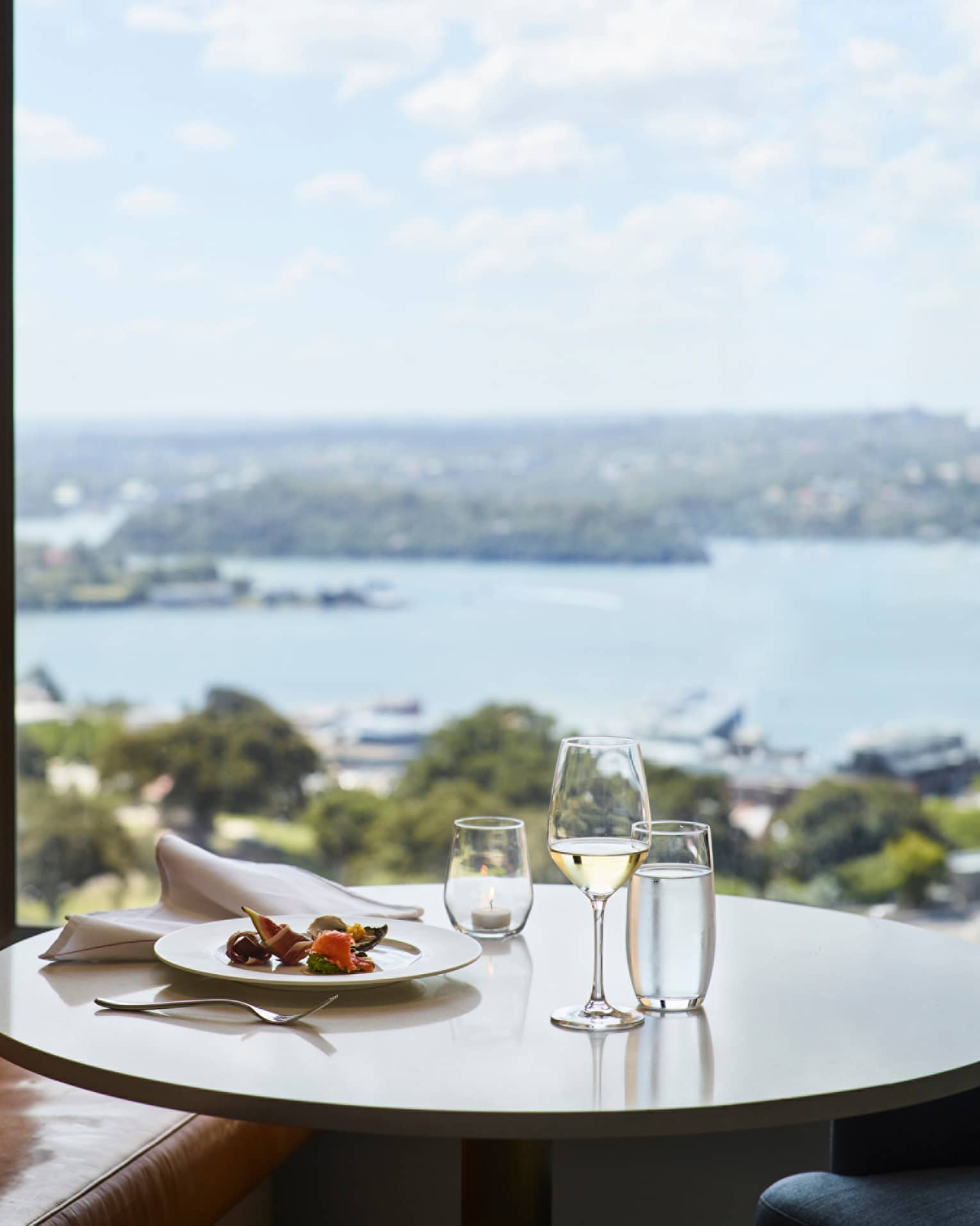 Lounge 32 meal, glass of white wine on round table by window with harbour views