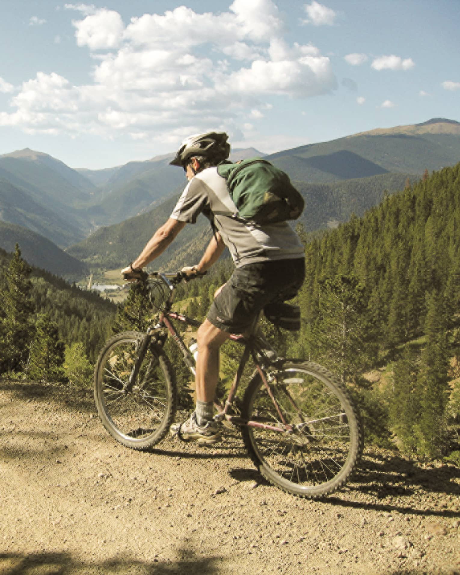 Man in shorts, Tshirt, helmet on bicycle on summer mountain bike trail