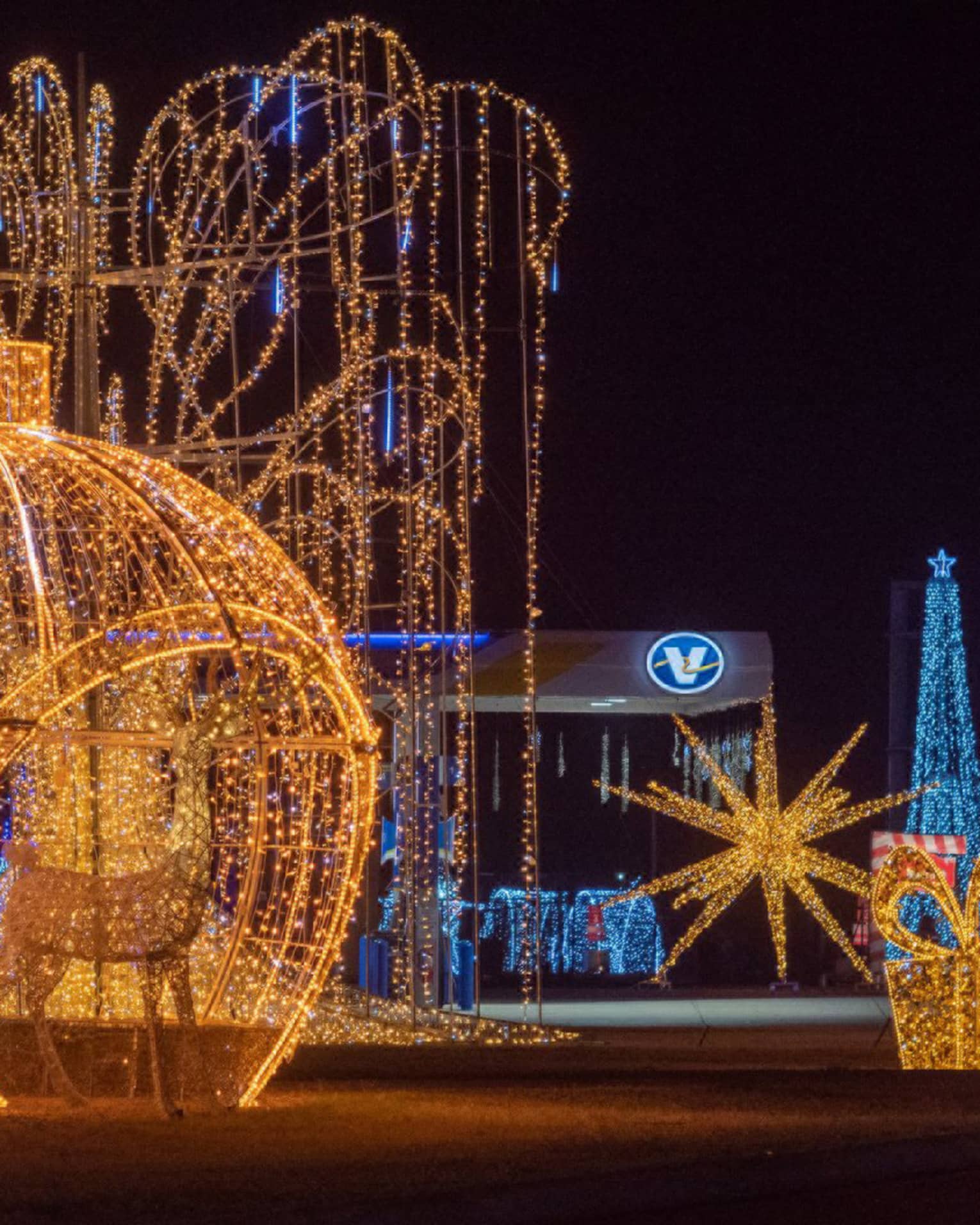 Large sculptures made out of metal and glowing Christmas lights including ornaments and presents.