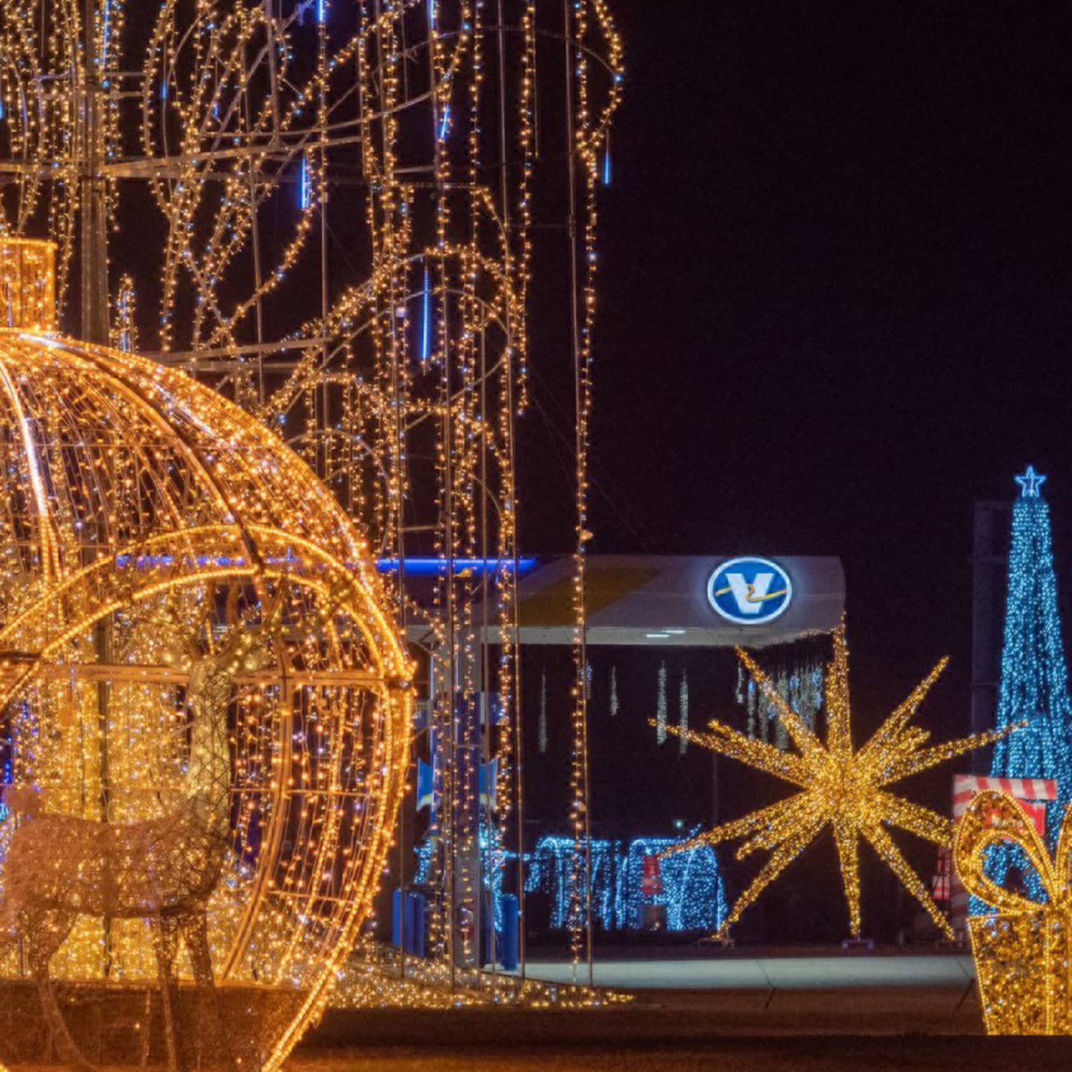 Large sculptures made out of metal and glowing Christmas lights including ornaments and presents.