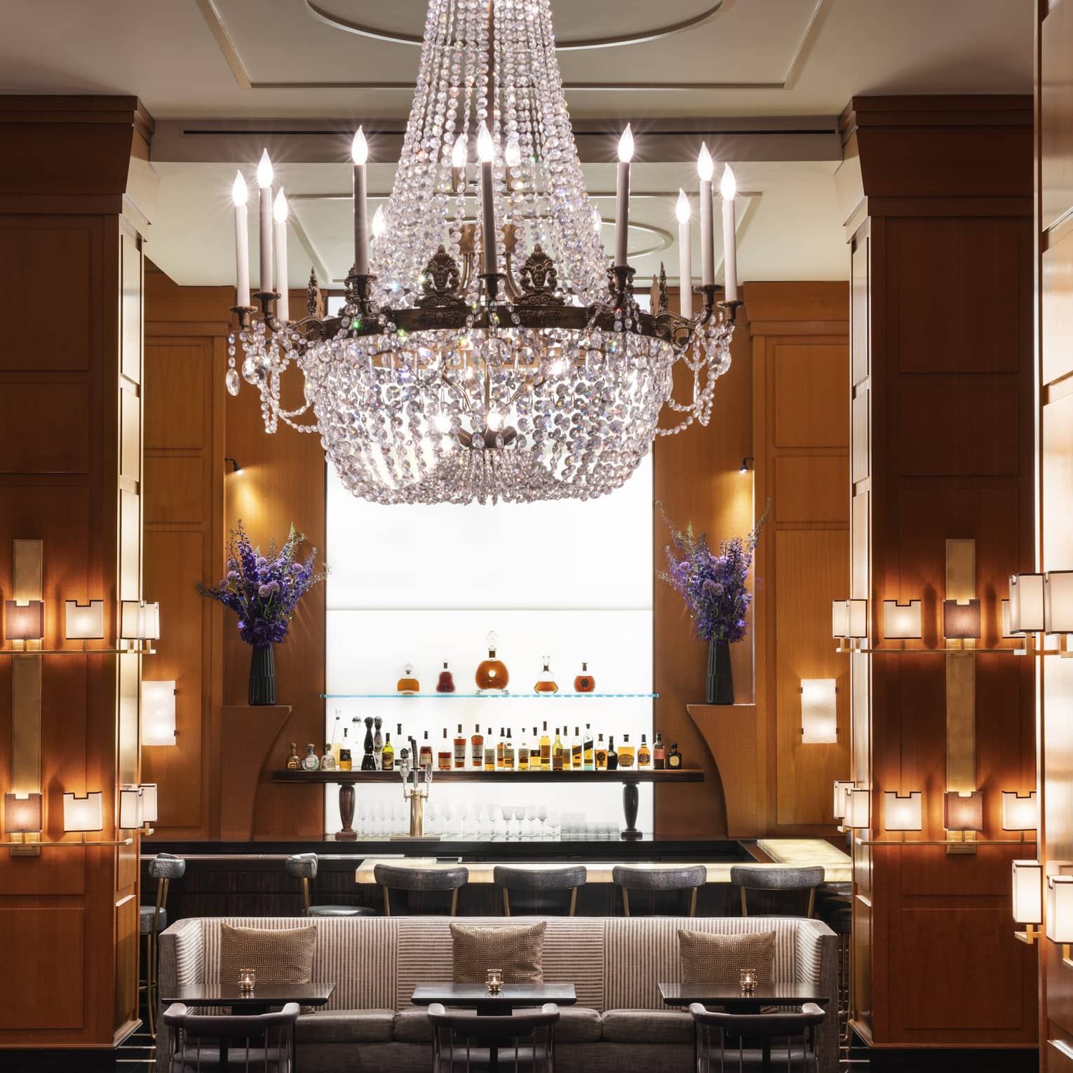 A bar area with a large chandelier and small lights on the walls.