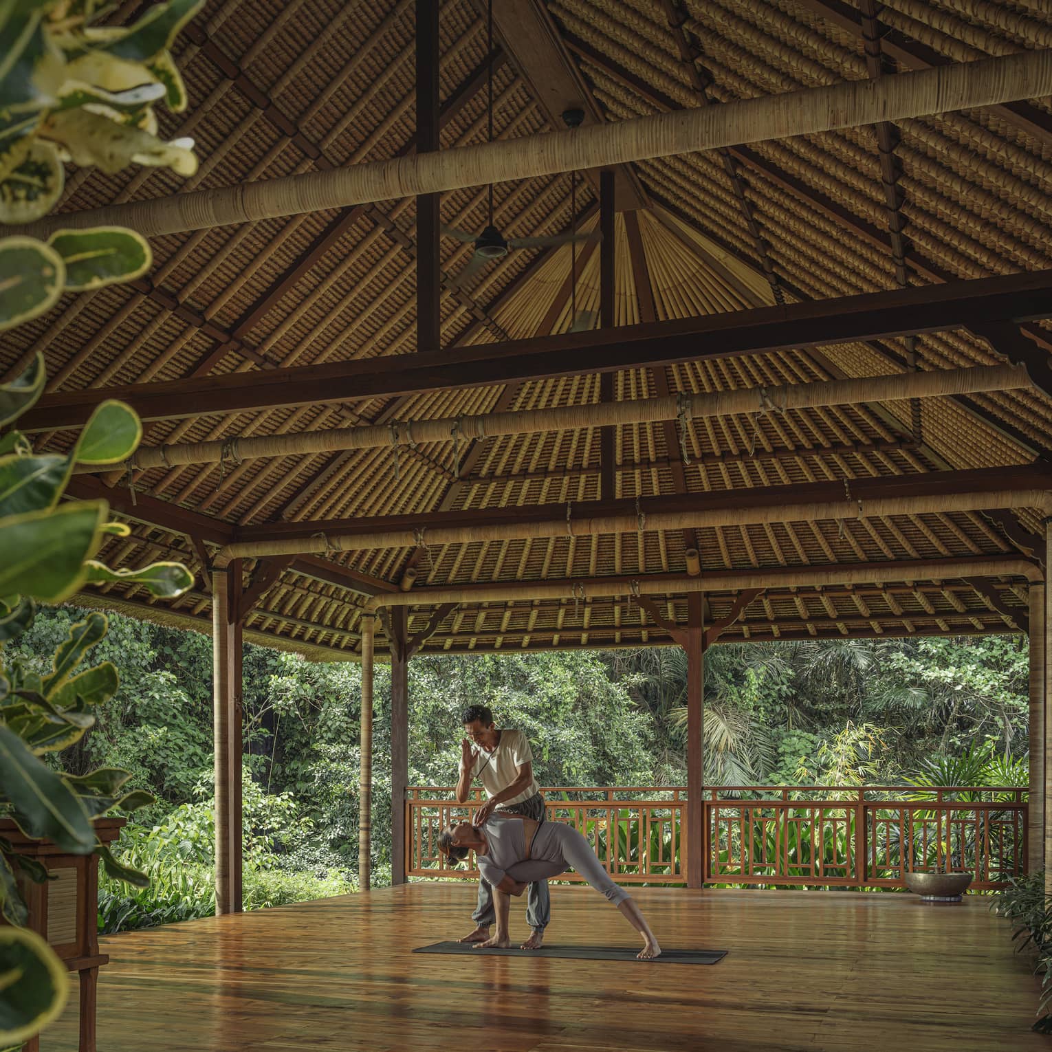 Instructor guides guests into yoga pose in outdoor pavilion