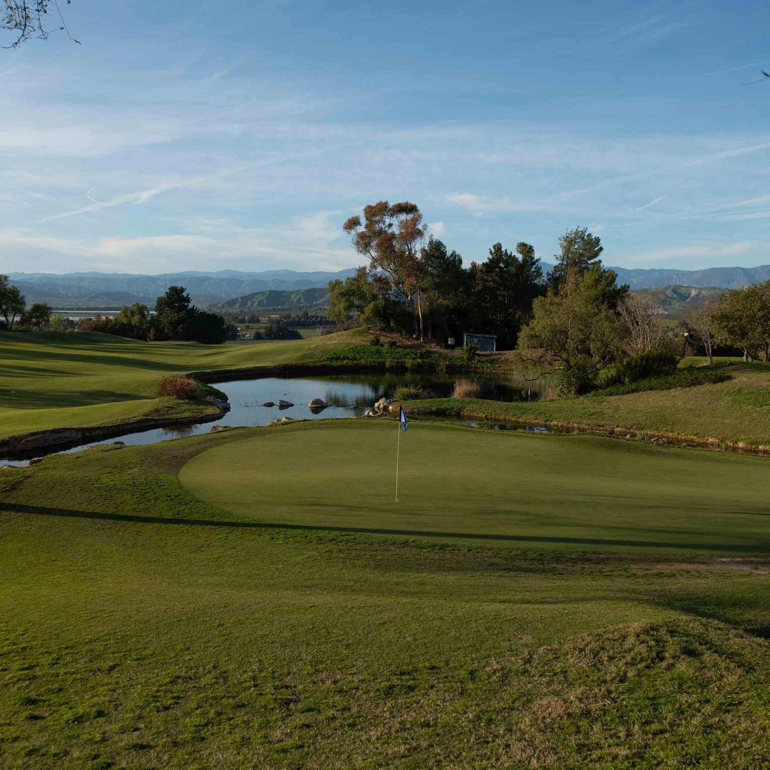 Golf course green with a water feature in the near distance