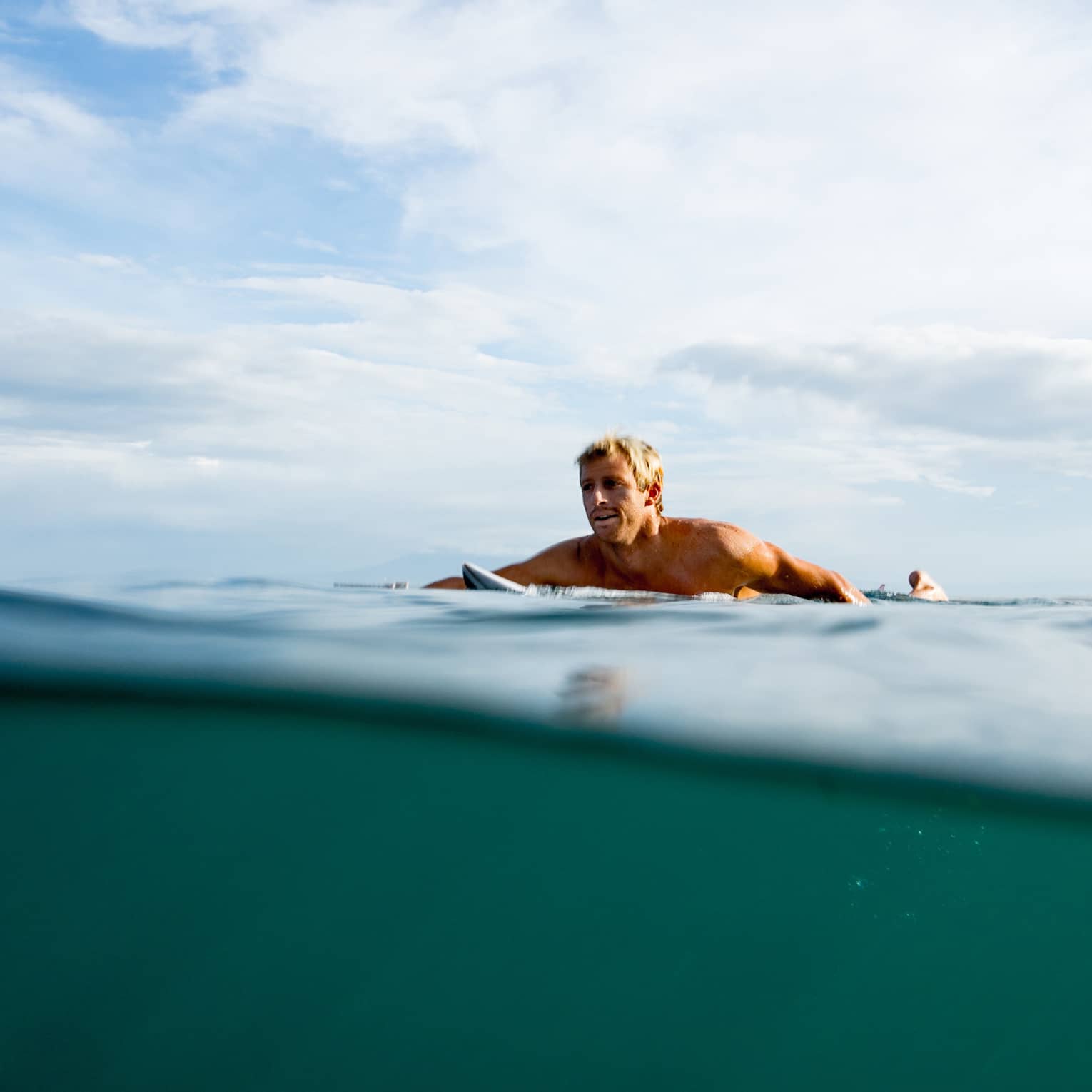 A guest swims out to surf on the water in Bali