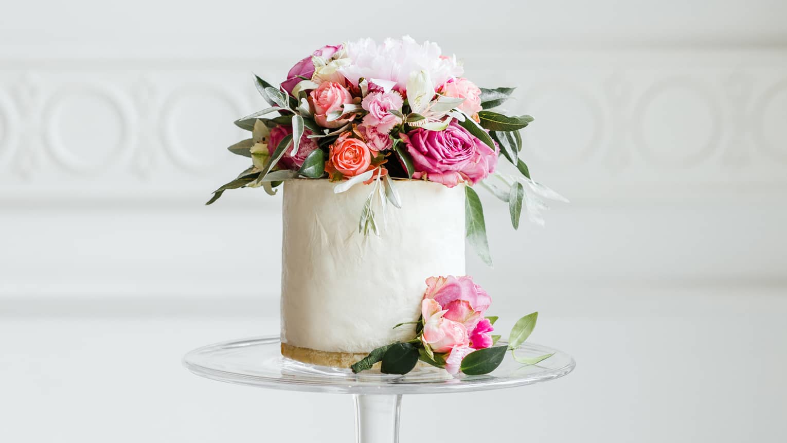 Elegant small white wedding cake topped with fresh pink and white roses 
