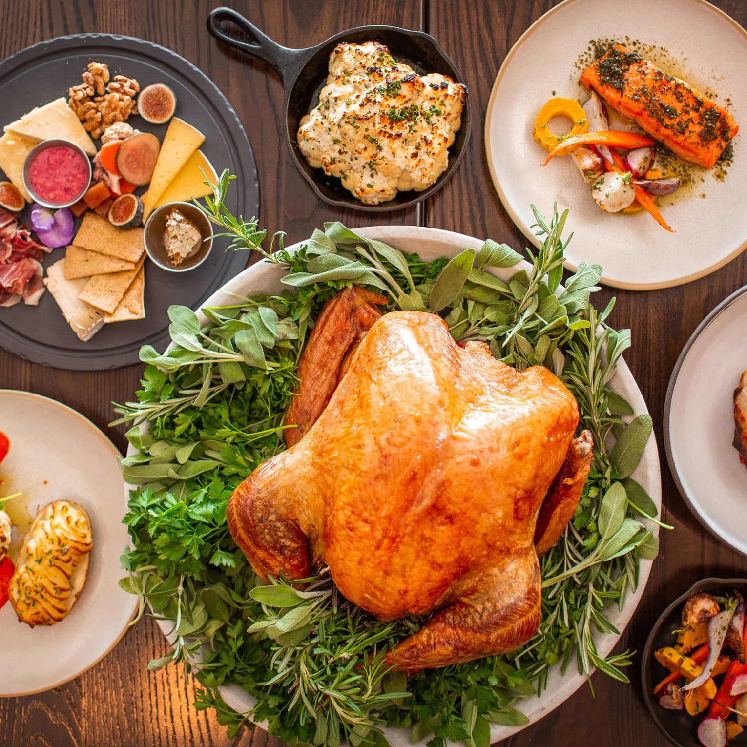An assortment of thanksgiving food including Turkey, charcuterie, vegetables, and more.