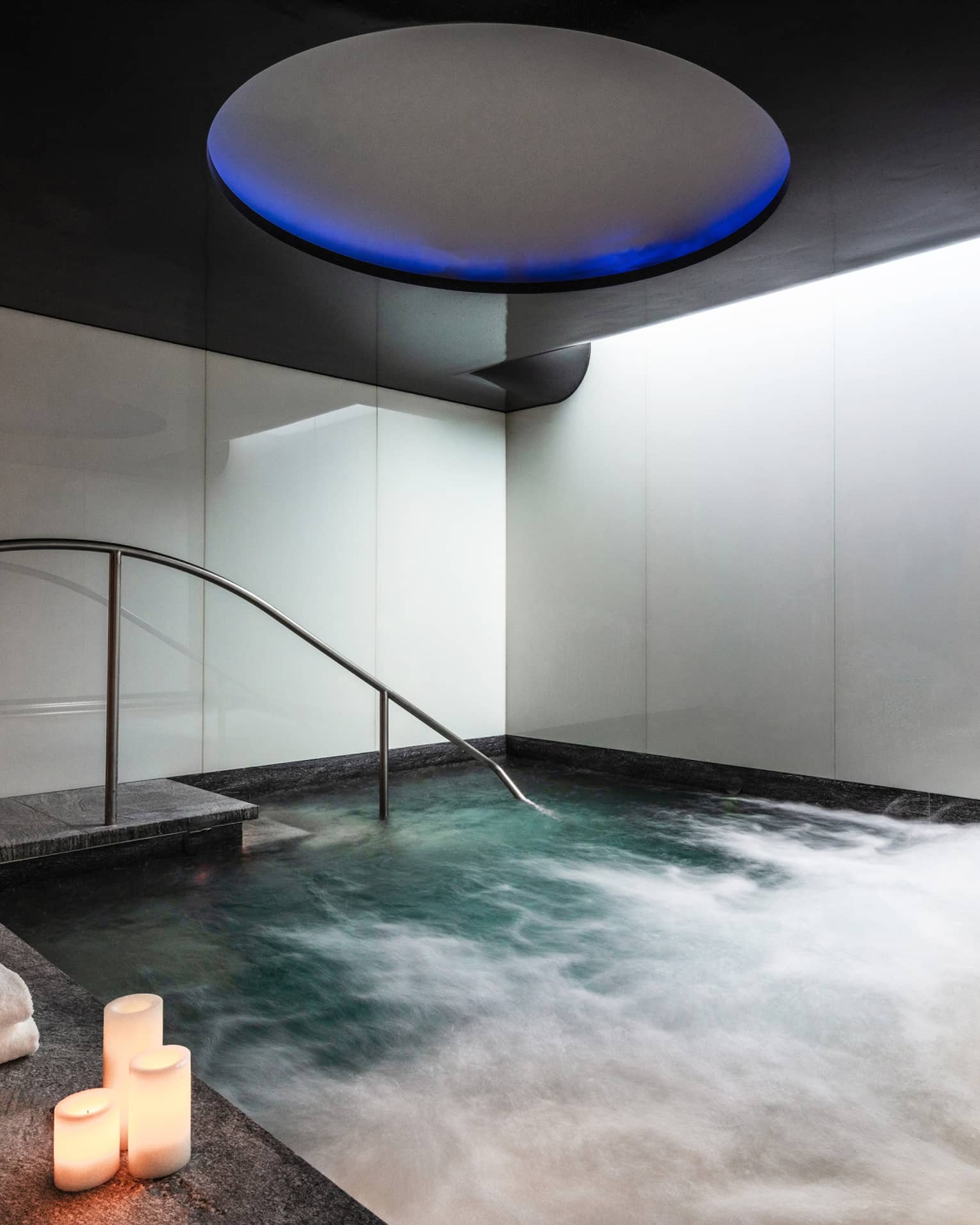 An indoor whirlpool with candle on the ledge.
