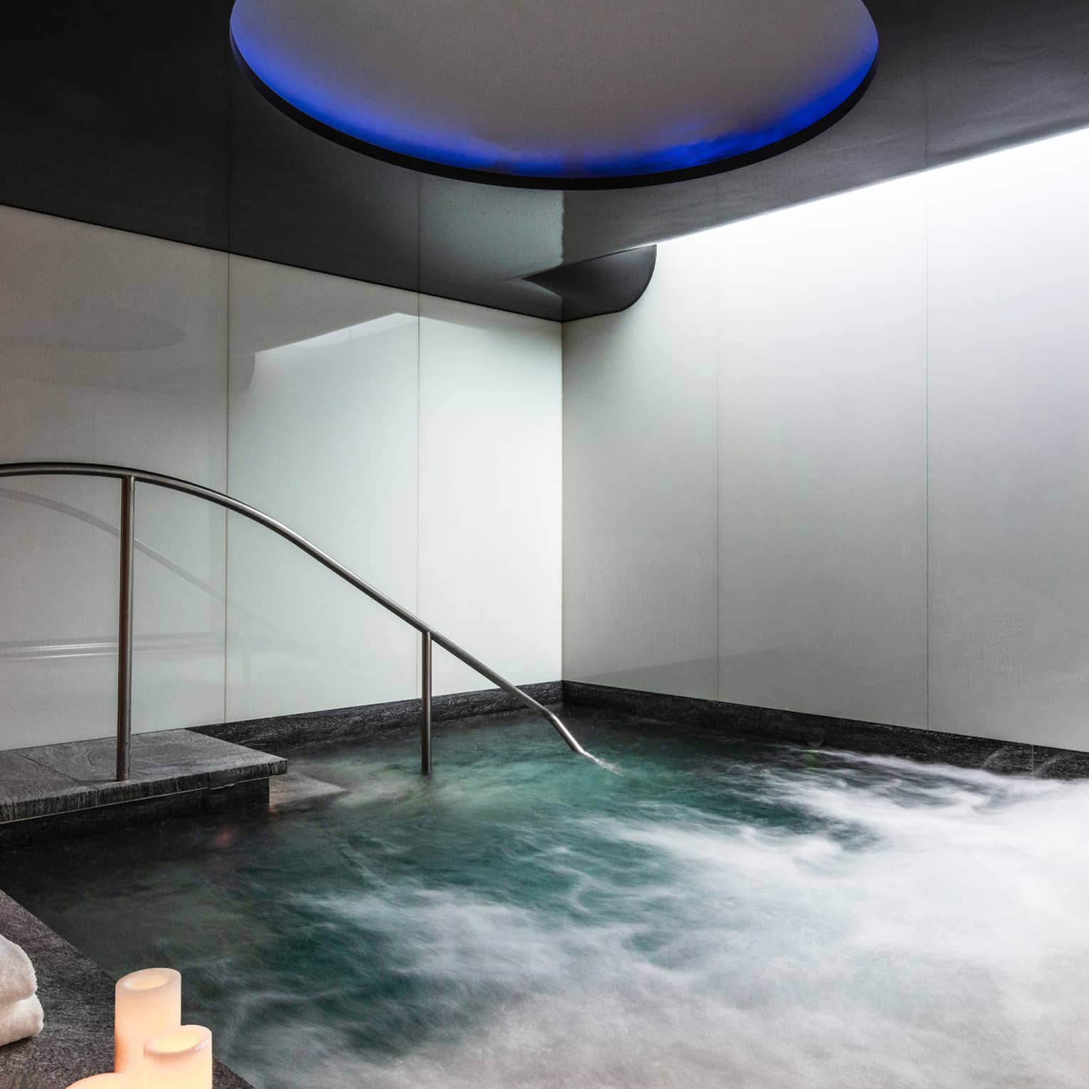 An indoor whirlpool with candle on the ledge.